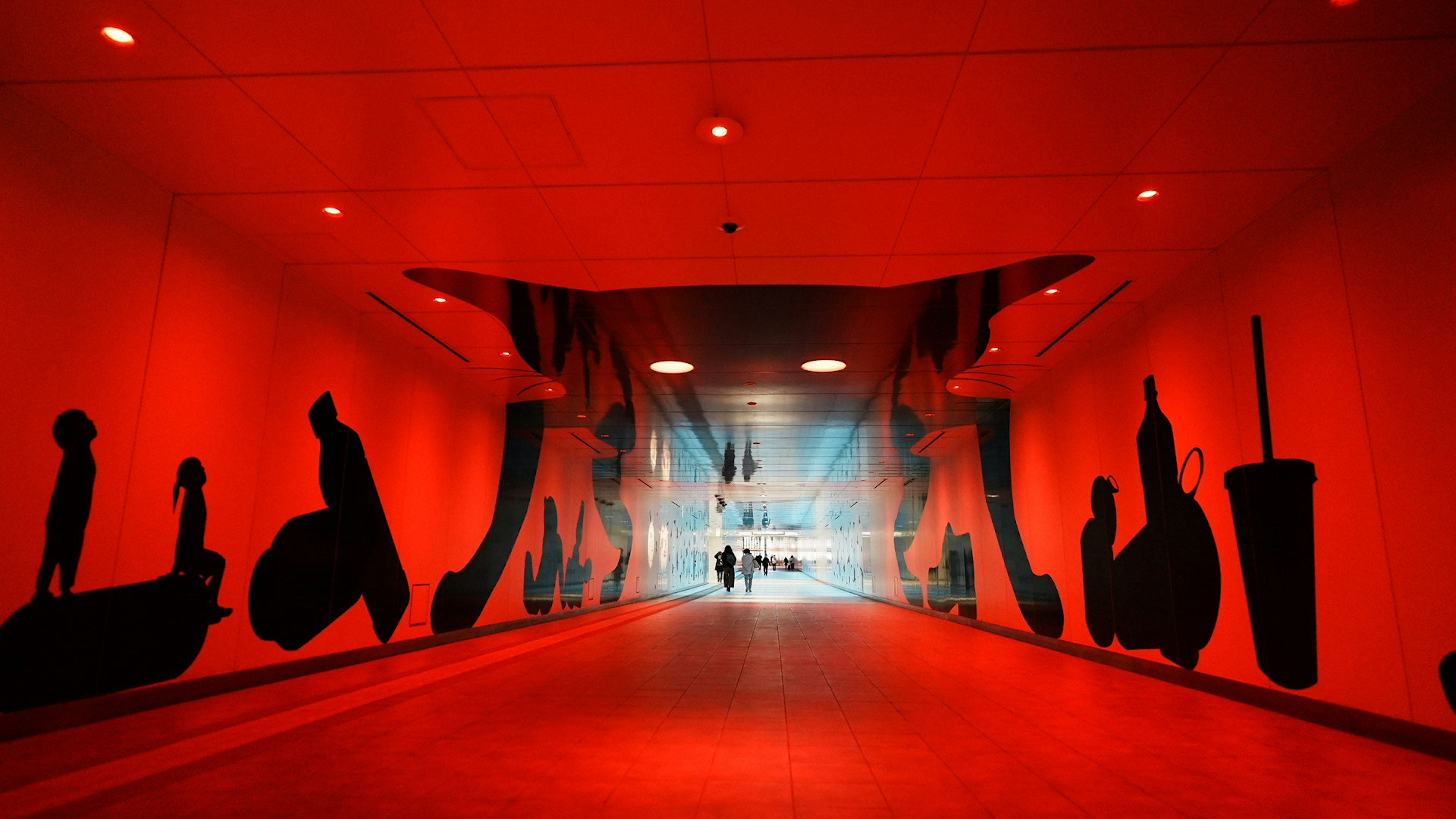 Un tunnel rouge avec des silhouettes de personnes et d'objets