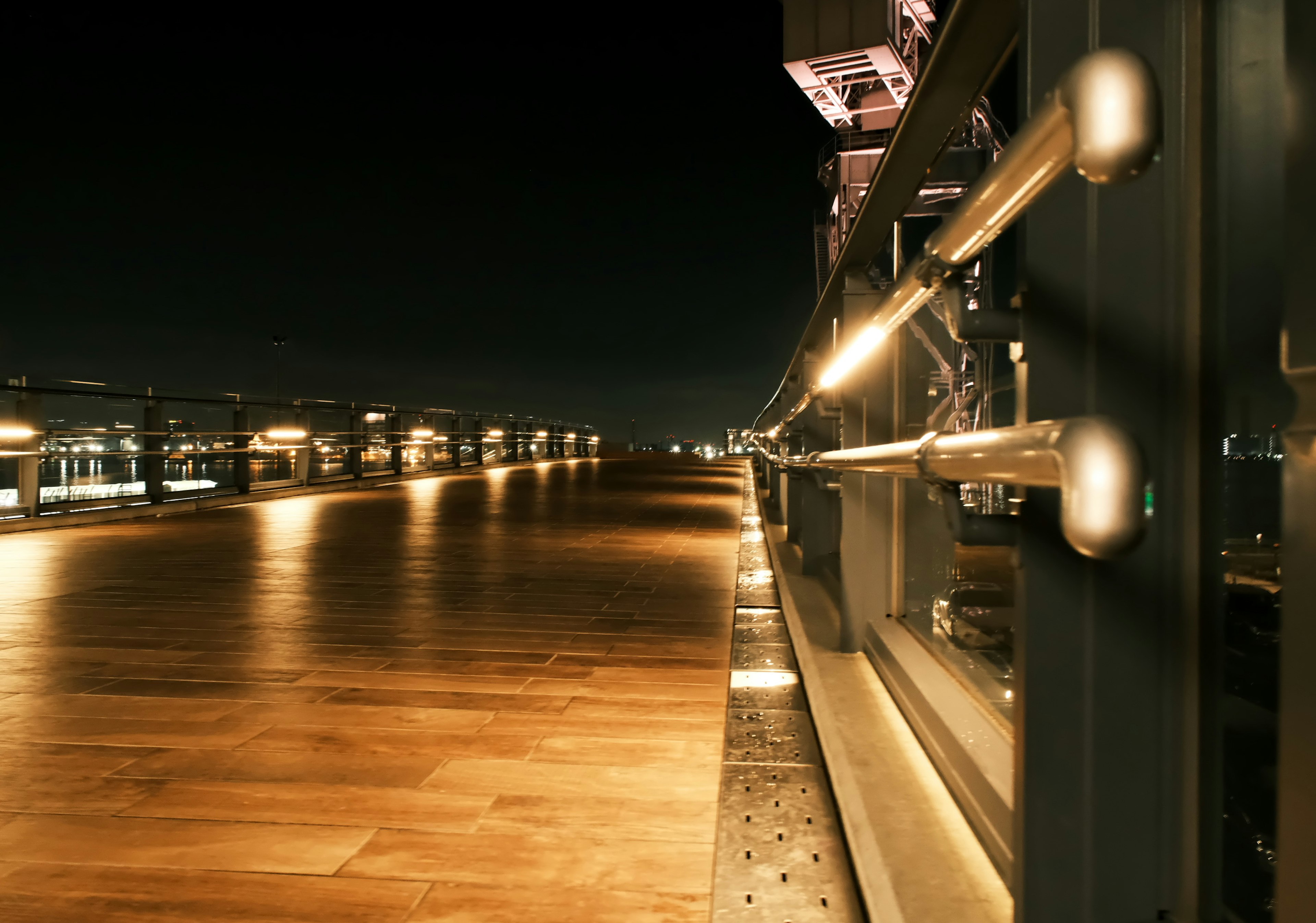 Vista notturna con pavimento in legno illuminato e ringhiera in metallo