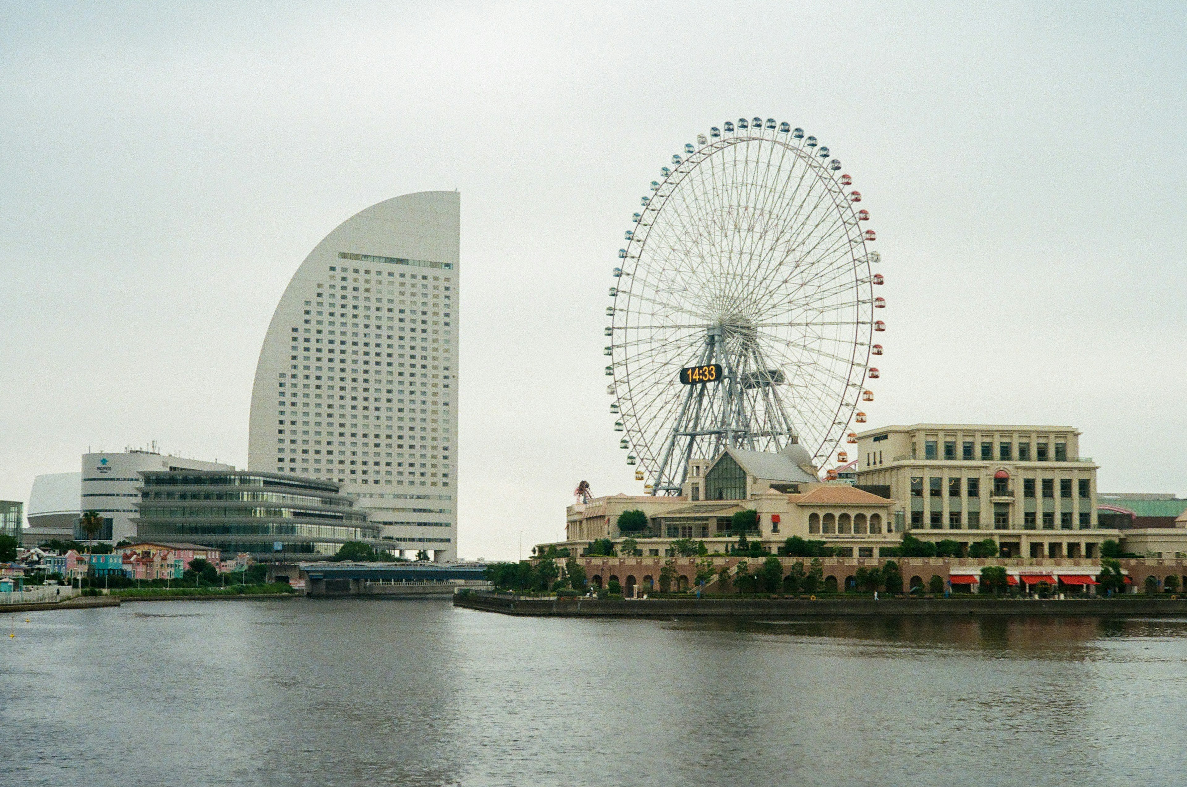 Paisaje de Yokohama con una noria y arquitectura moderna junto al agua