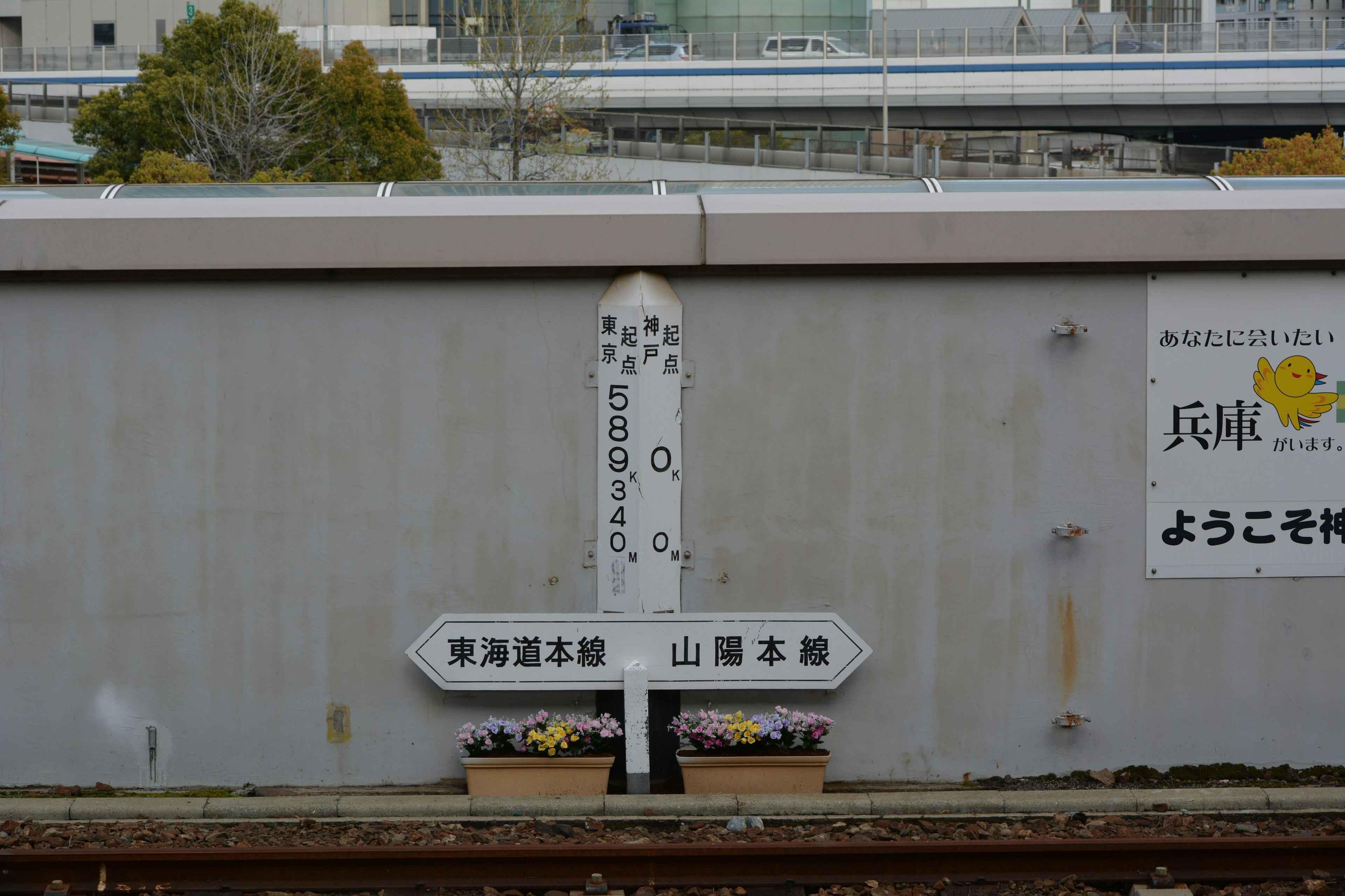 Señal de estación de tren con macizo de flores