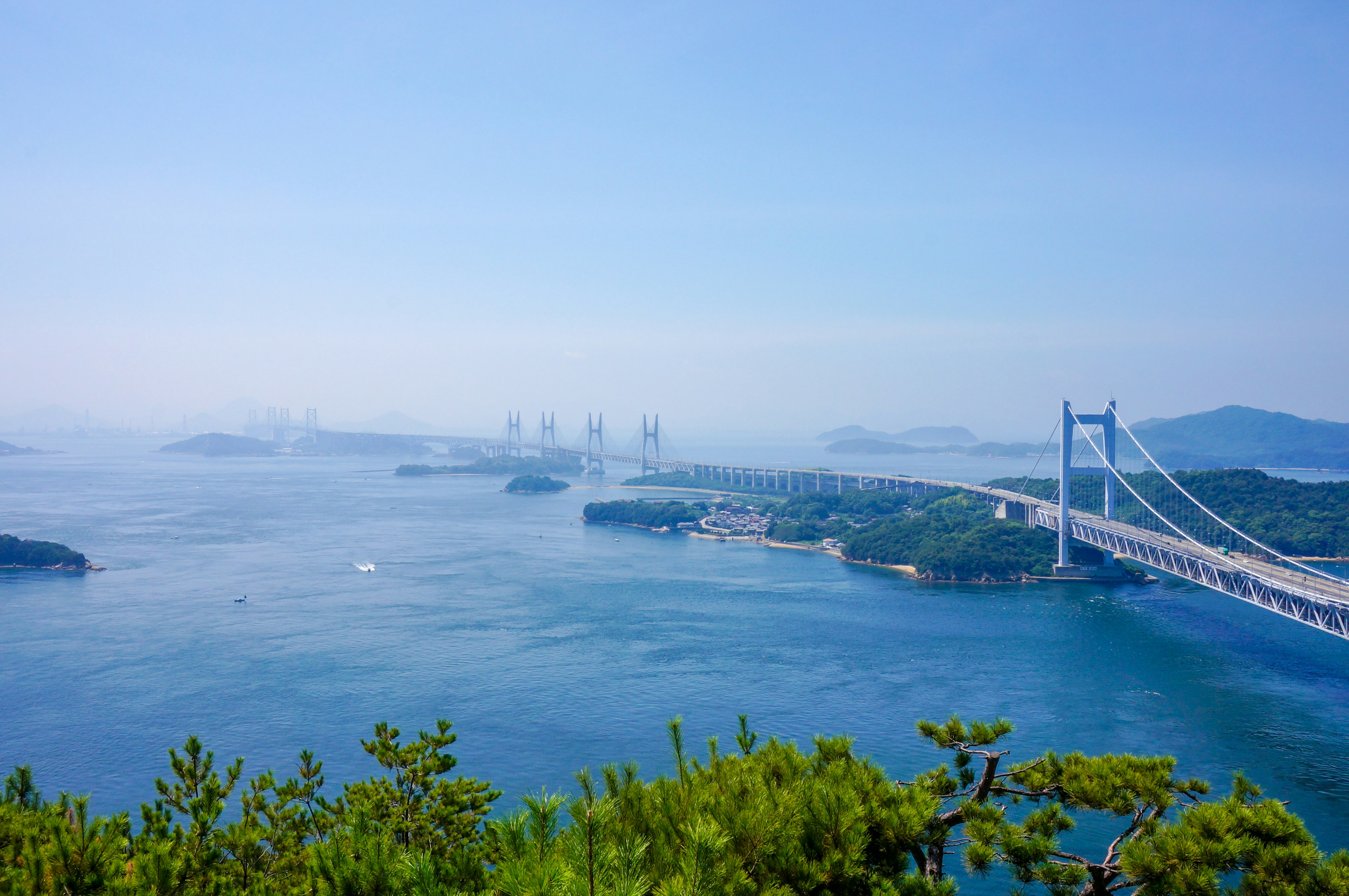 Pemandangan laut biru dengan jembatan dan pulau di latar belakang