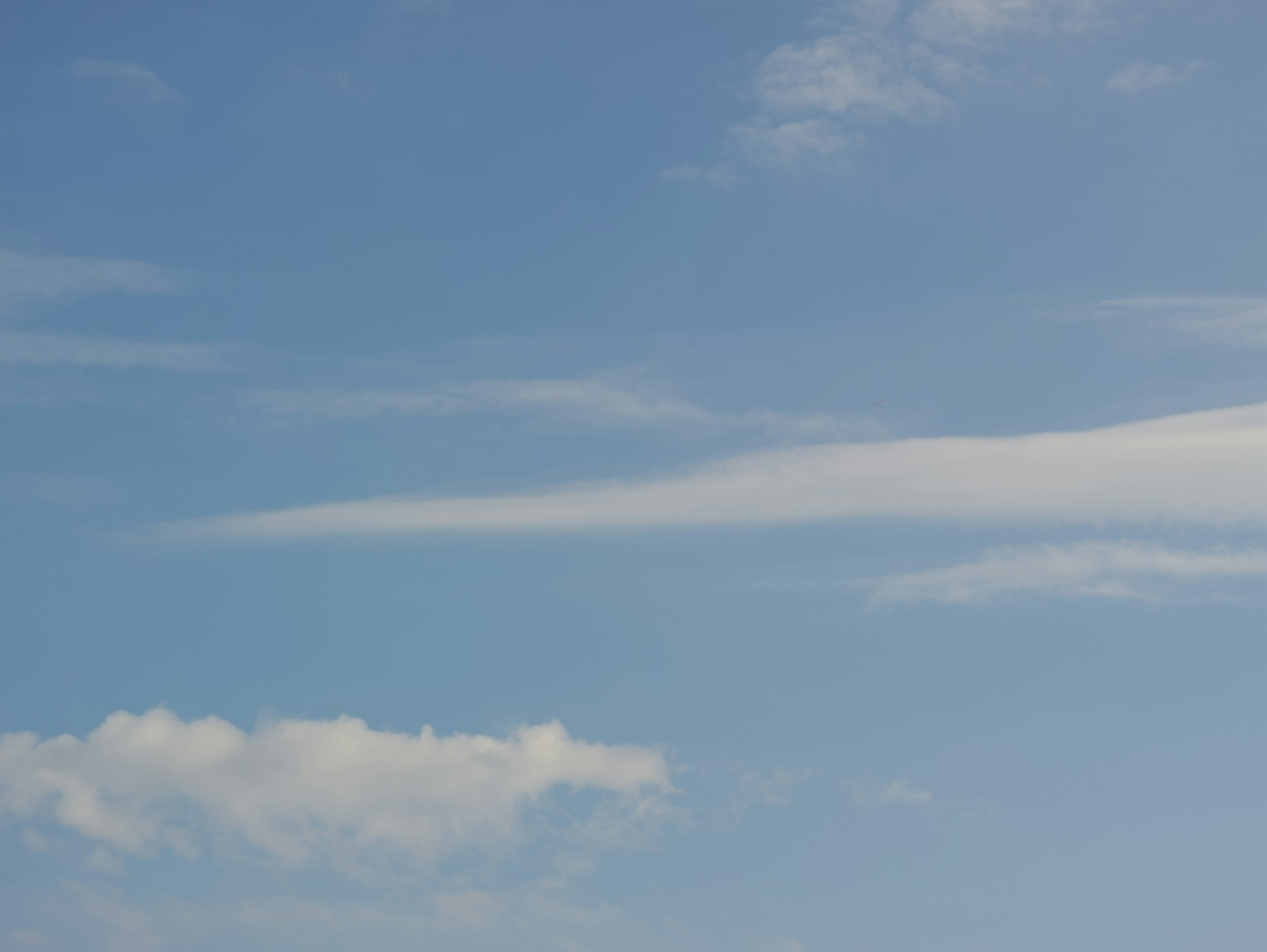 Un ciel bleu clair avec des nuages blancs filandreux