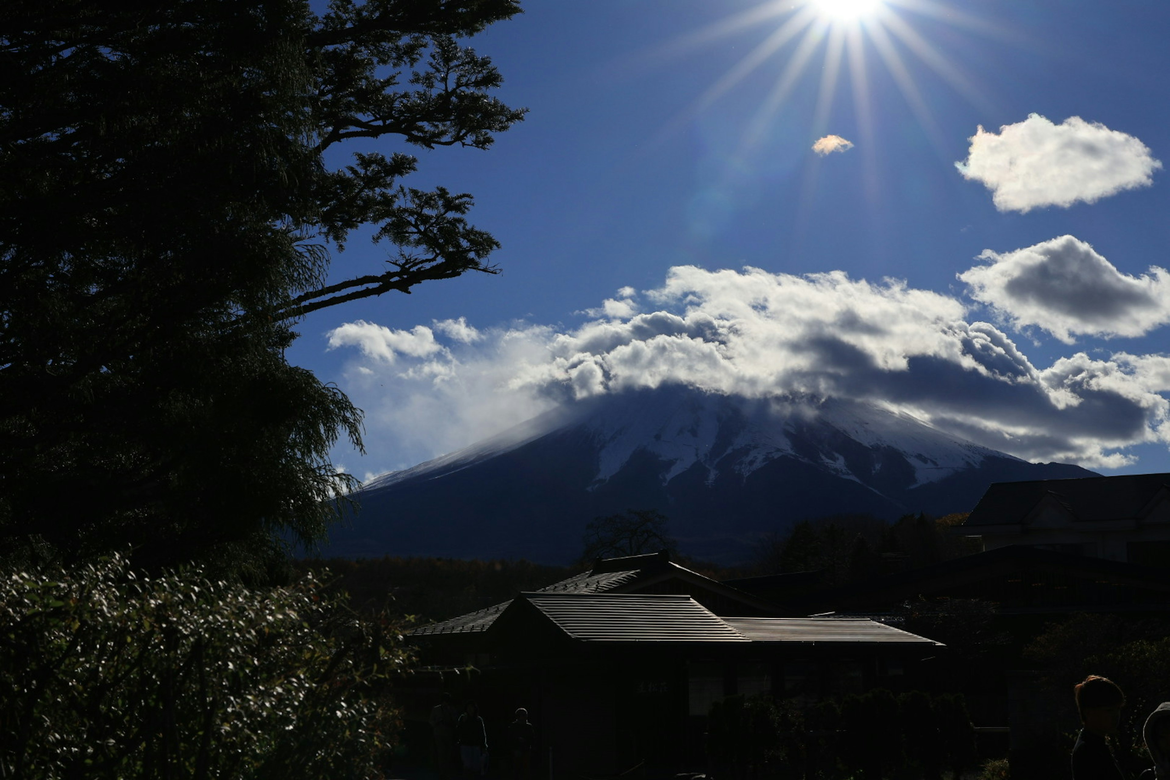 青空と雲に囲まれた山々と太陽の光が差し込む風景