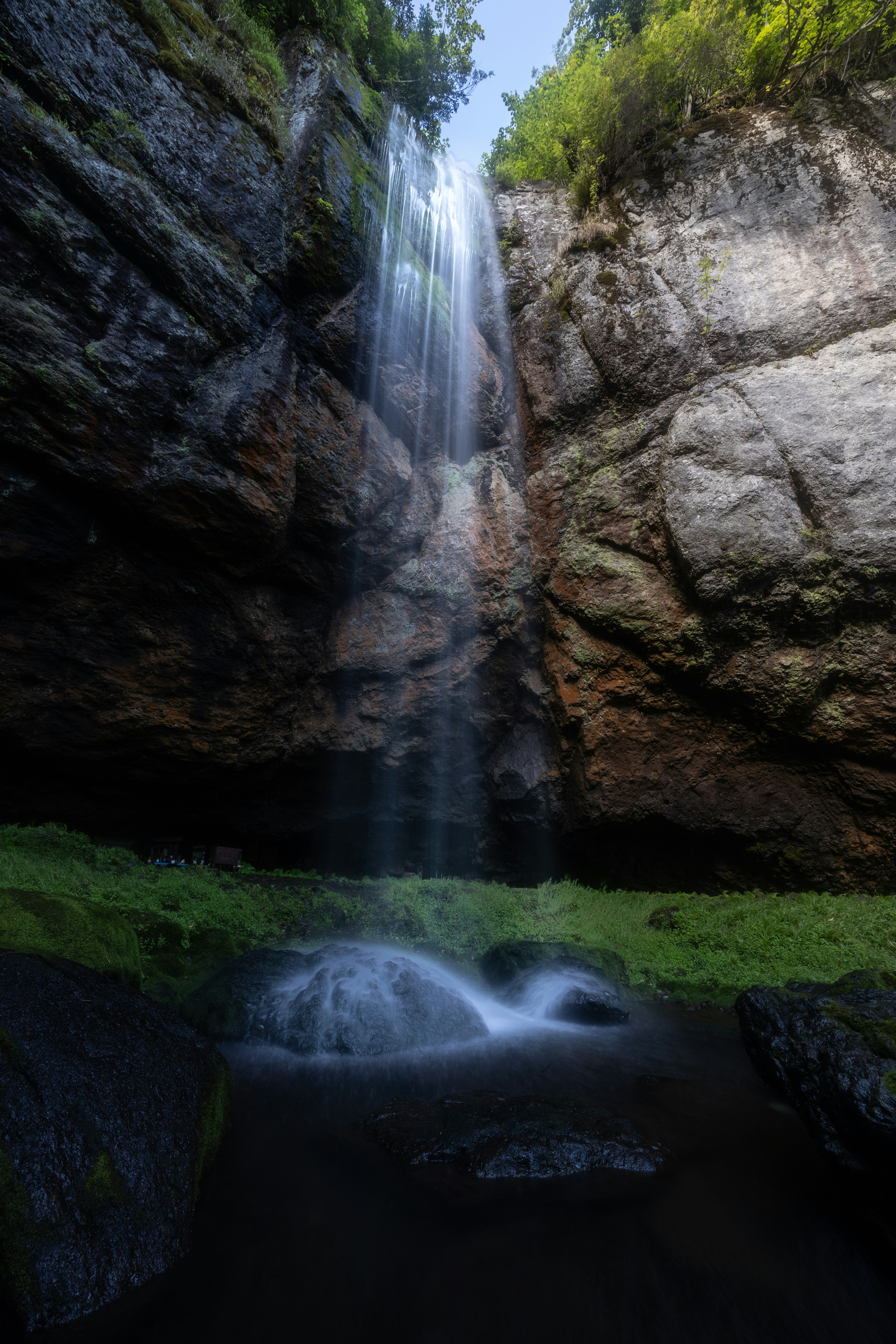 Air terjun megah mengalir dari tebing berbatu dikelilingi oleh vegetasi subur