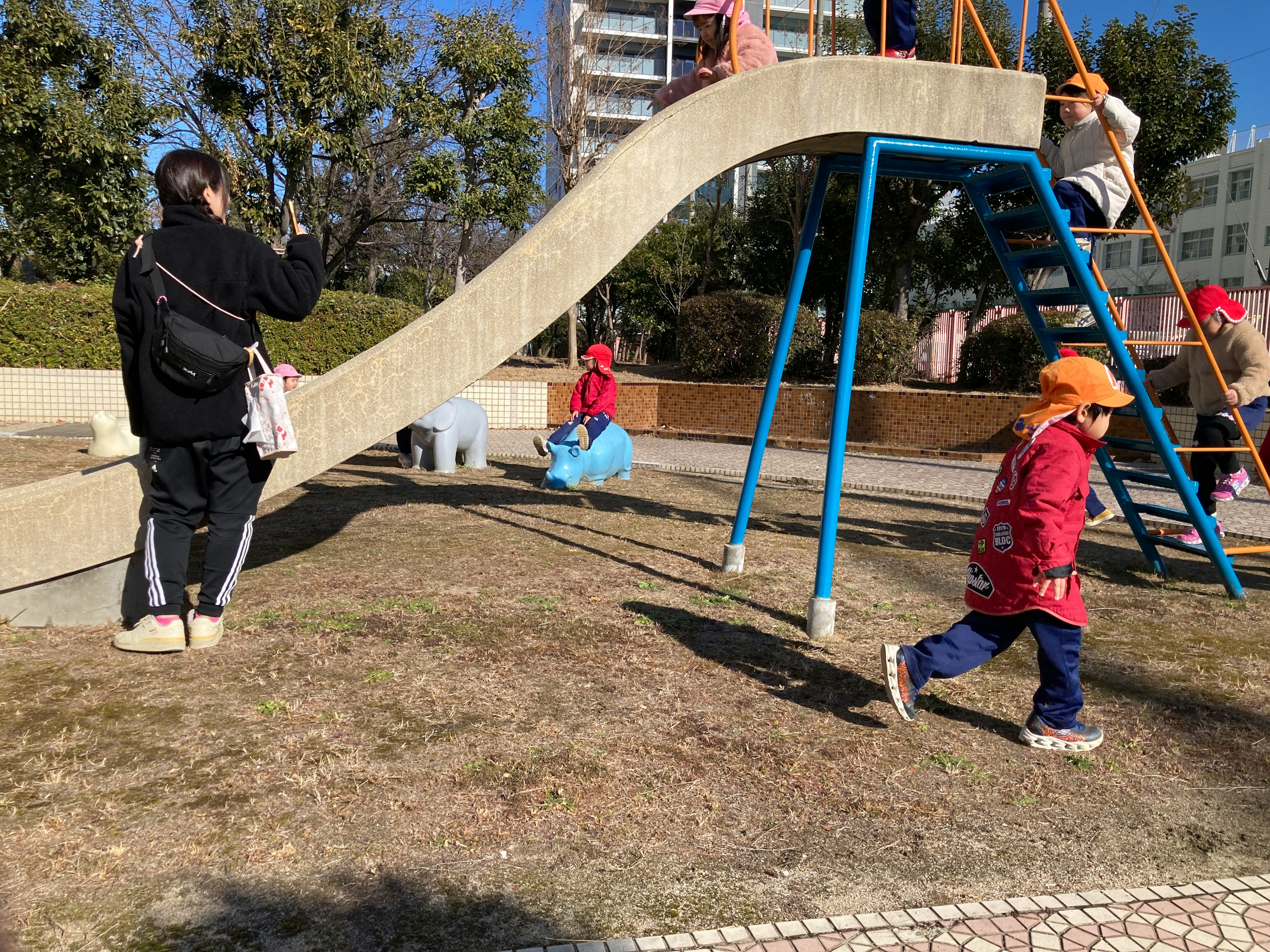 Niños jugando en un parque con un tobogán y equipos de juego