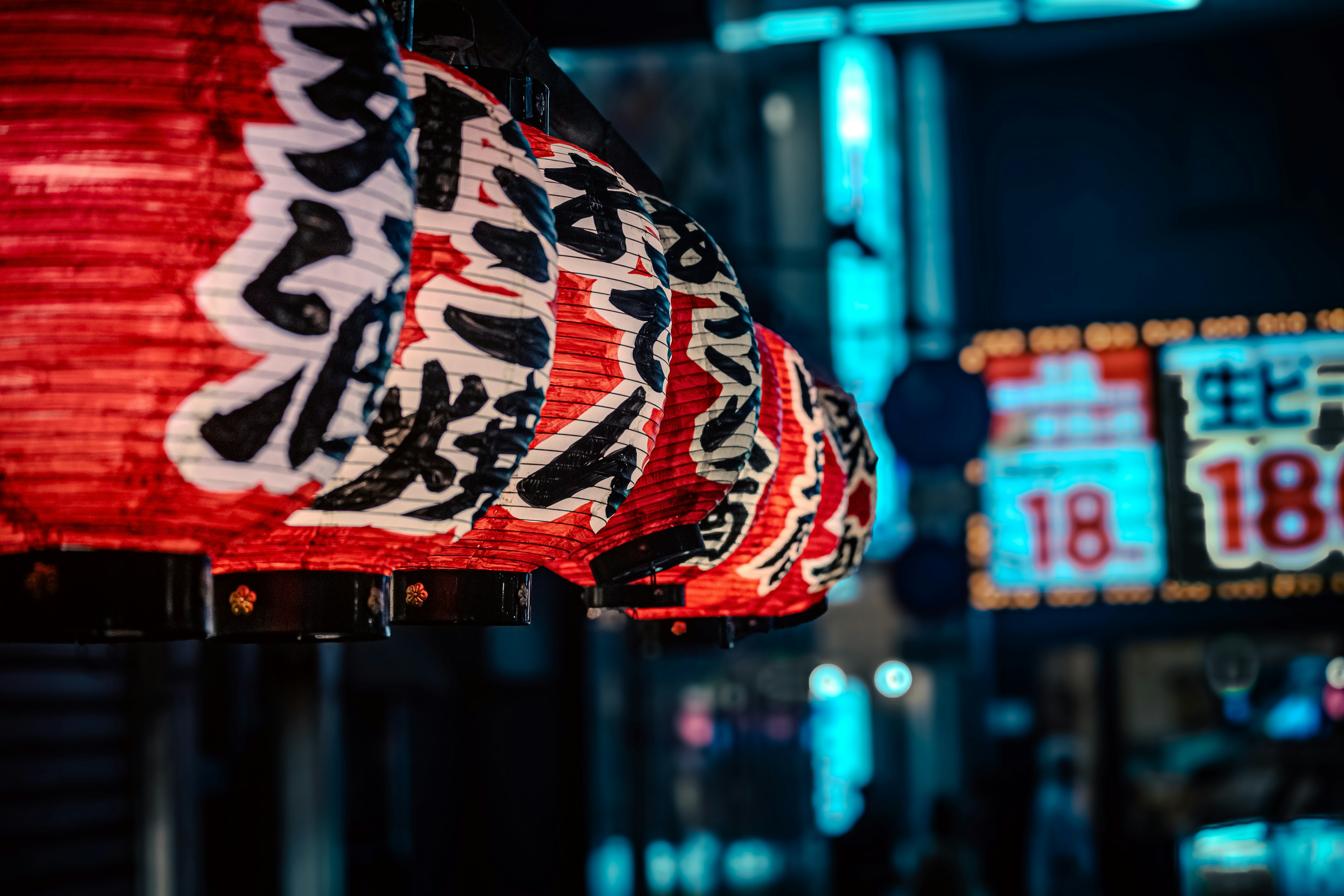 Red lantern with Japanese text illuminated in a nighttime street scene