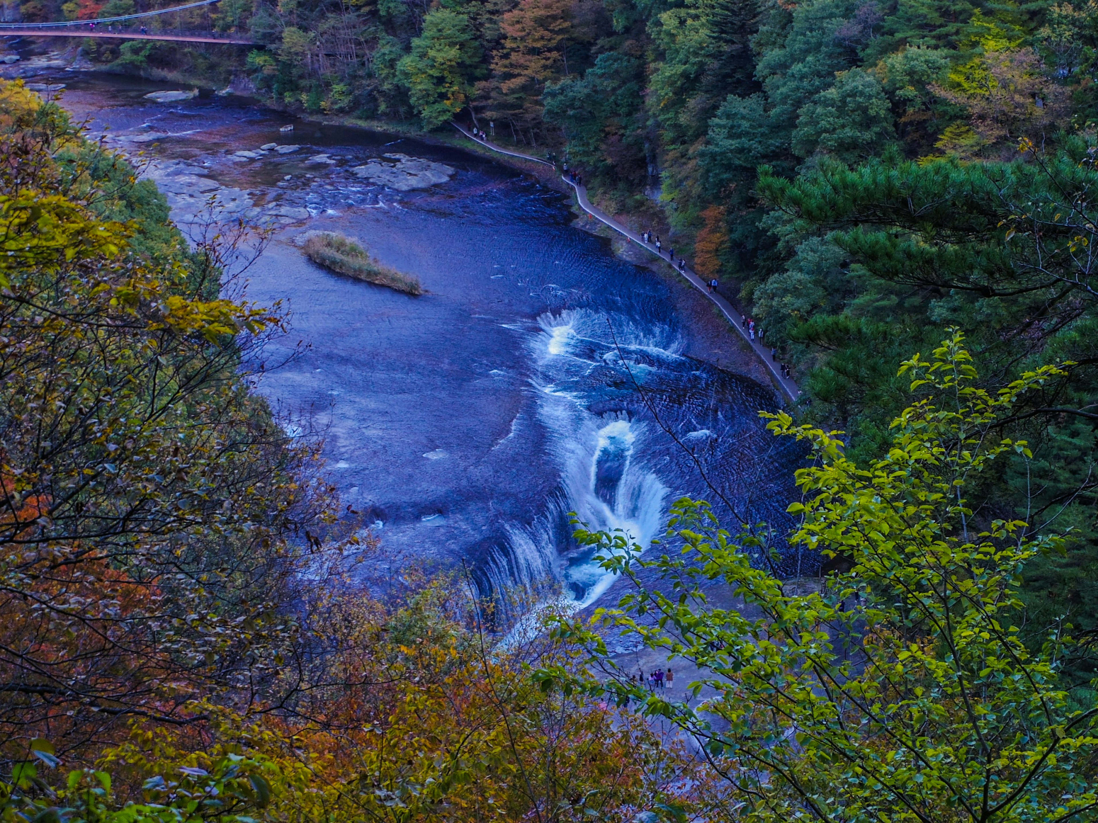 Vista escénica de un río y una cascada rodeados de un follaje otoñal colorido