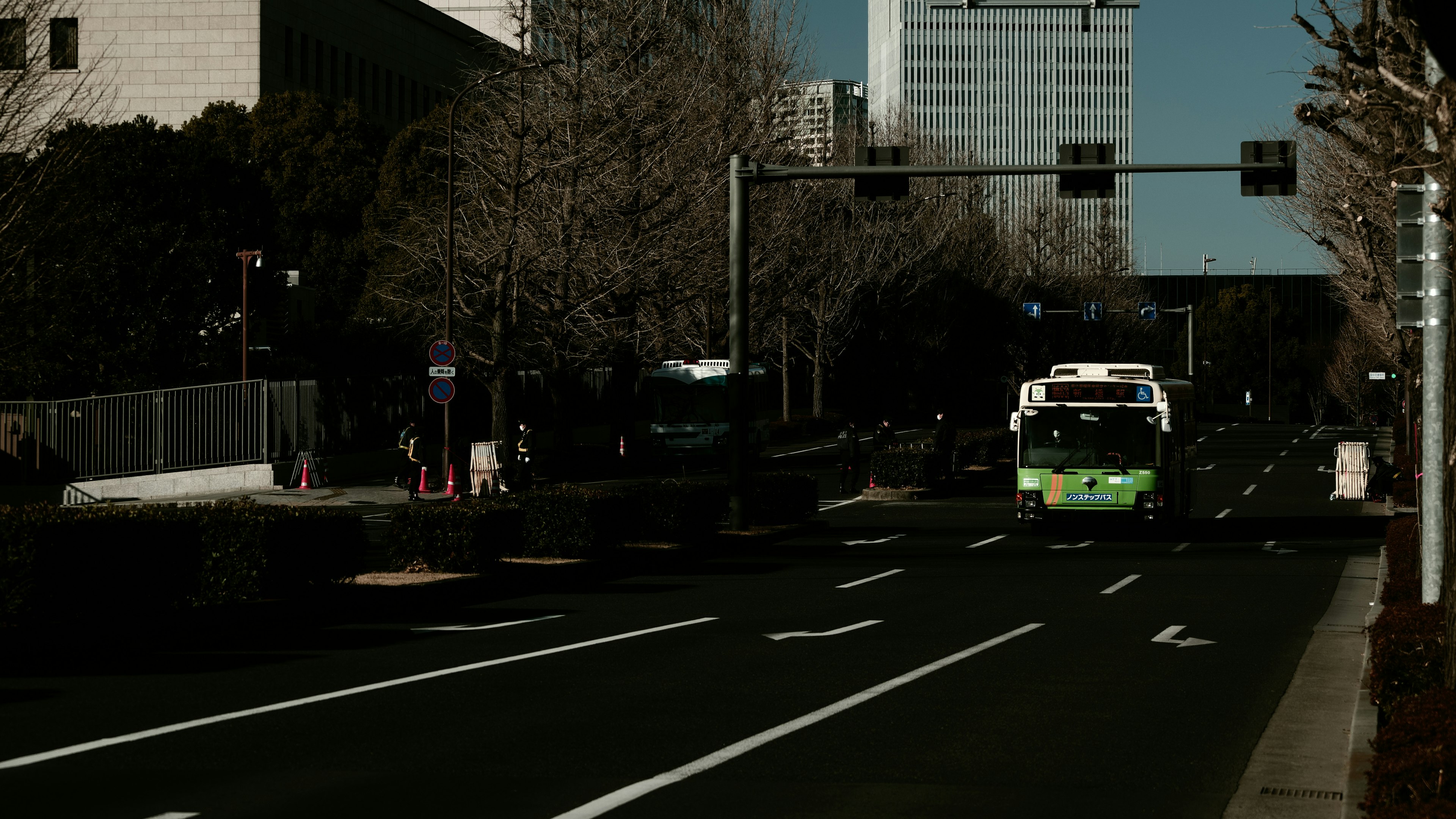 都市の通りを走る緑のバスとその他の車両