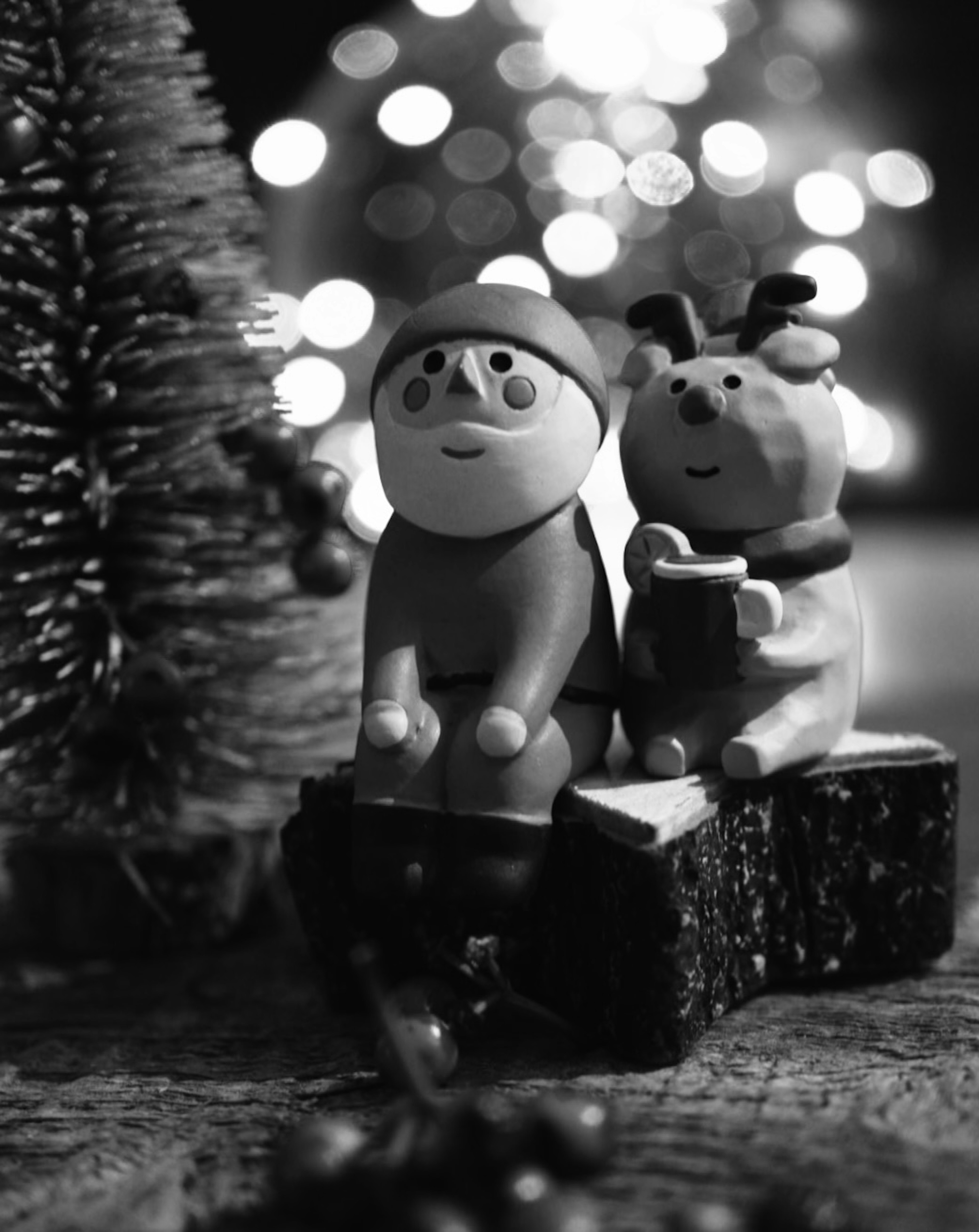 Foto en blanco y negro de Santa Claus y una figura de perro sentados frente a un árbol de Navidad