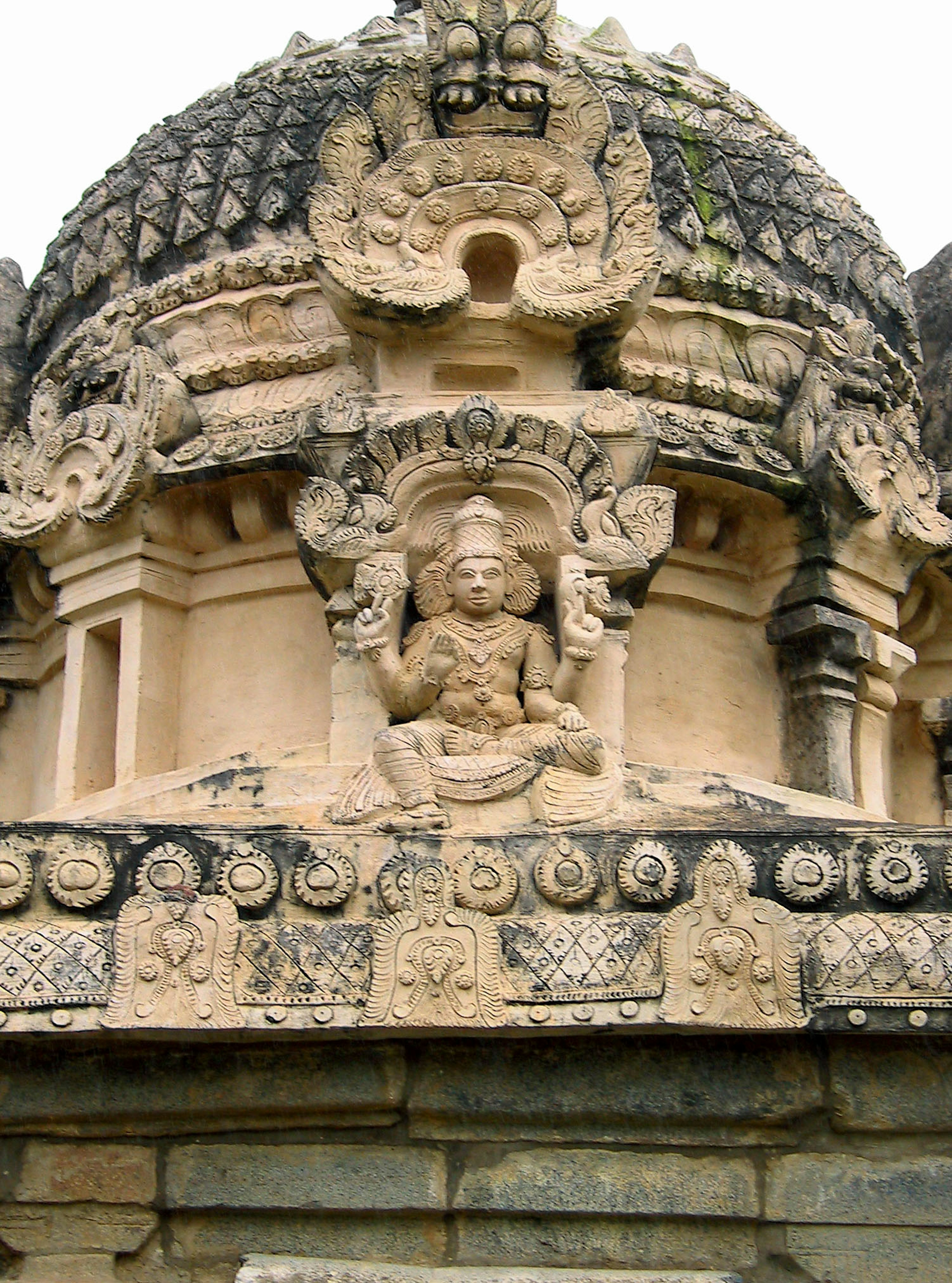 Dôme de temple ancien avec des sculptures complexes et une statue centrale entourée d'éléments décoratifs