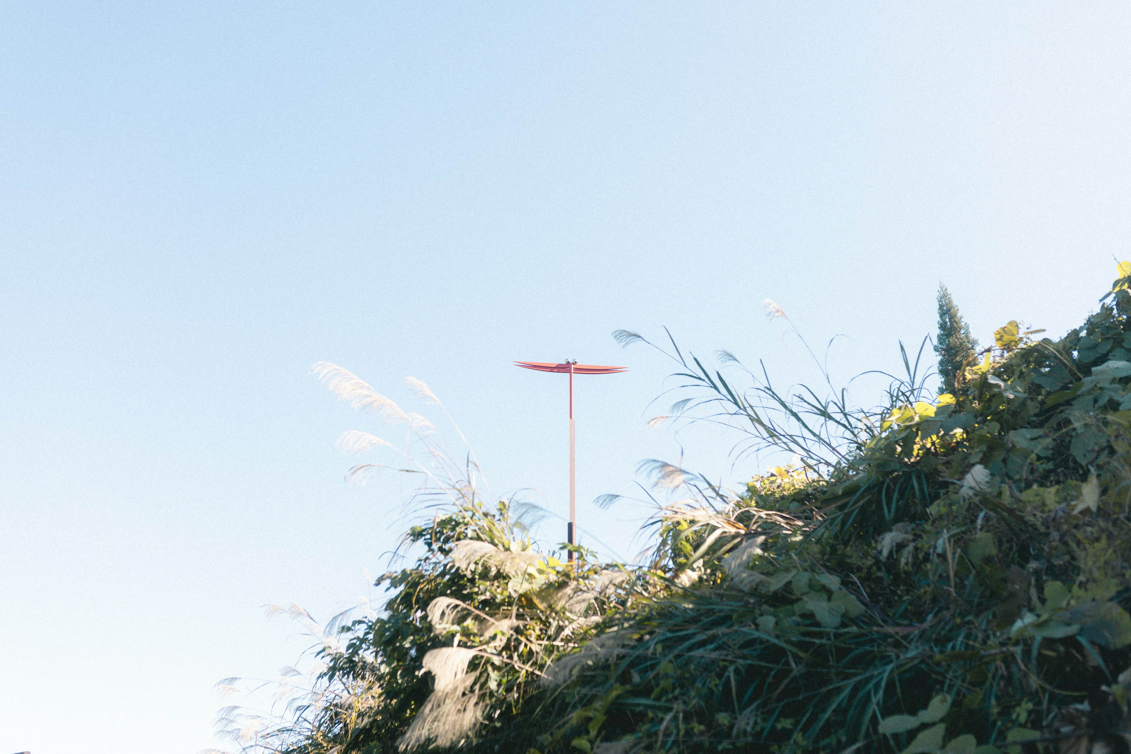 Red windmill against a blue sky above green hillside