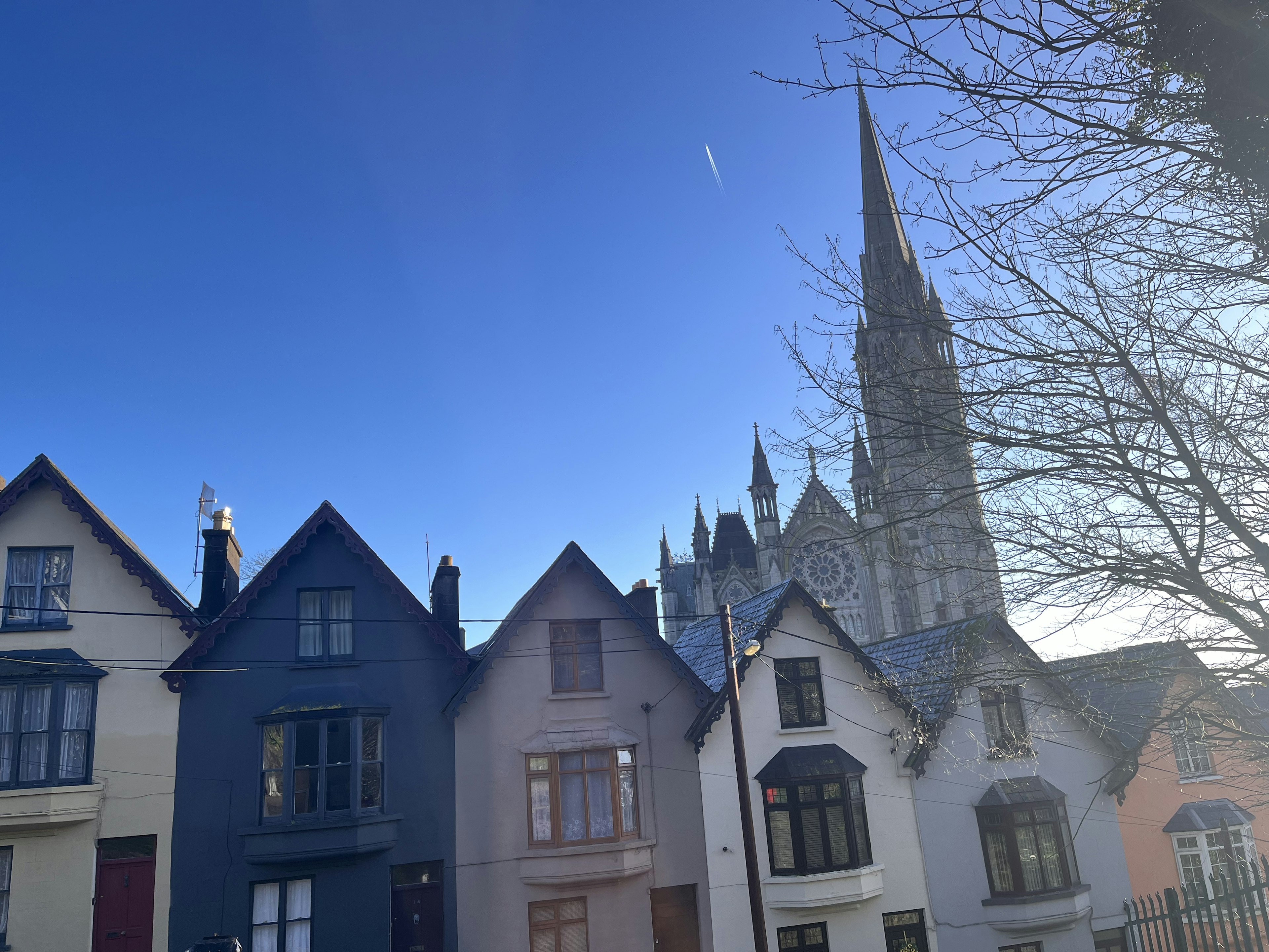 Colorful houses under a clear blue sky with a cathedral spire in the background