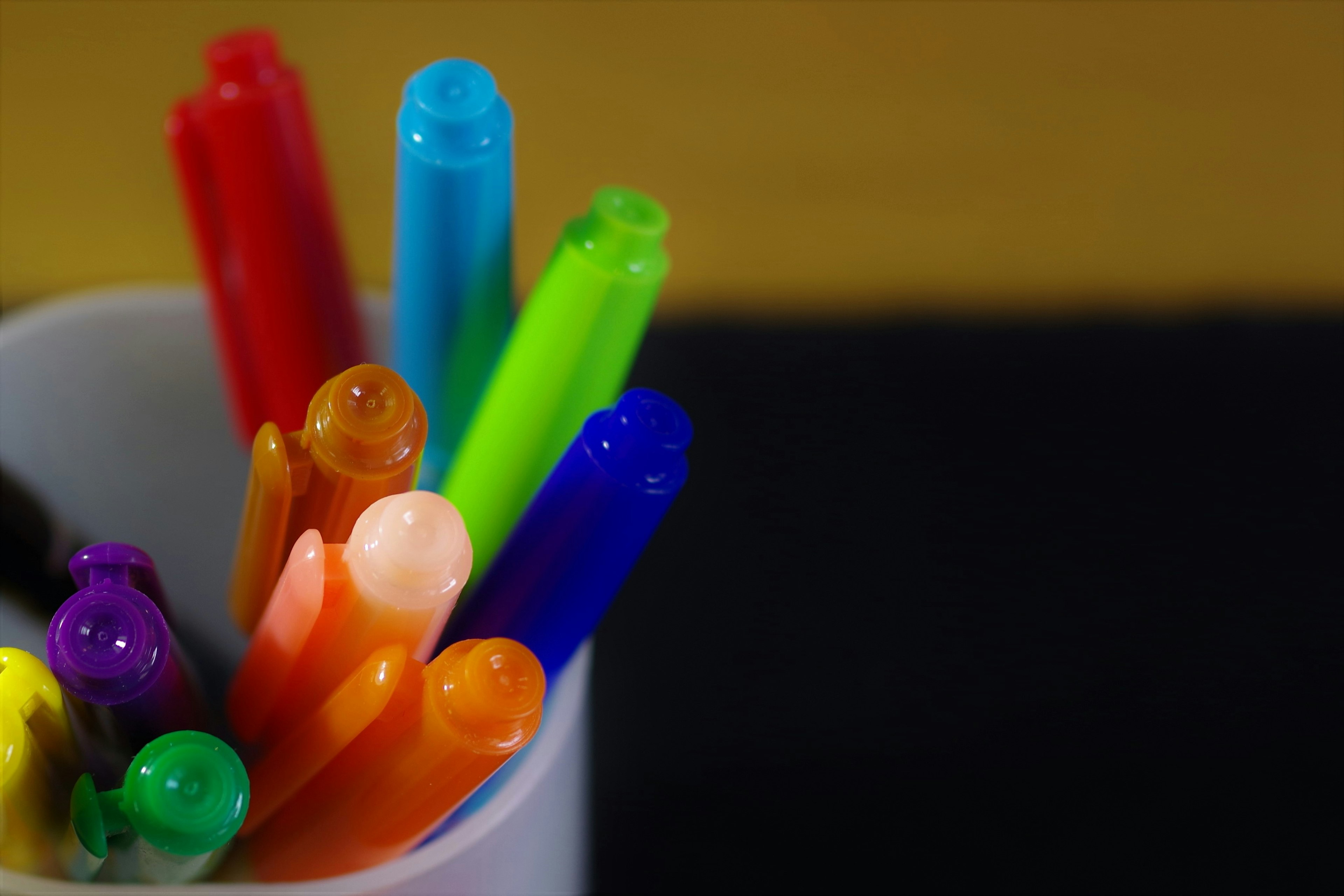 Gros plan de marqueurs colorés dans une tasse blanche