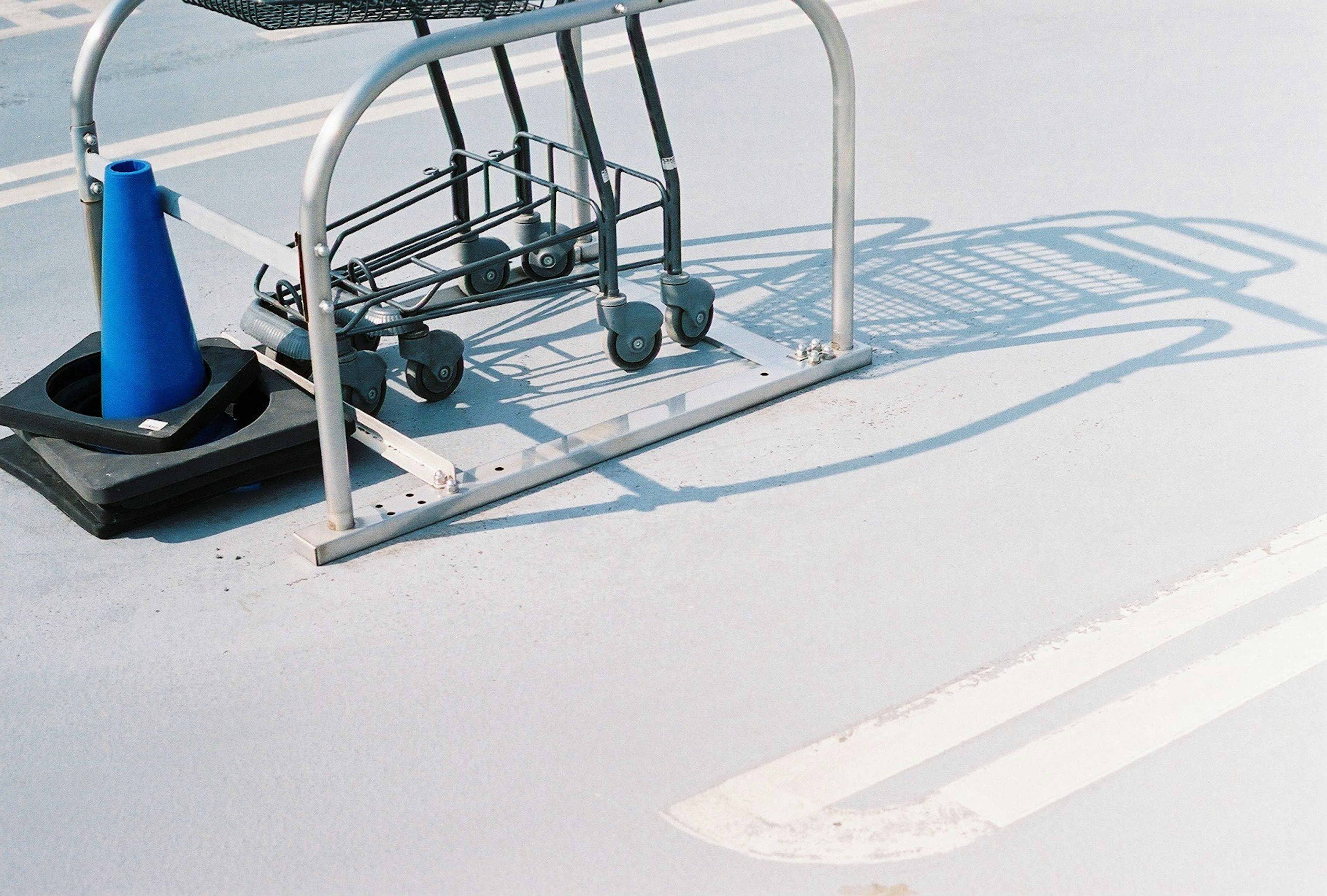 Einkaufswagen und blauer Kegel auf einem Parkplatzboden