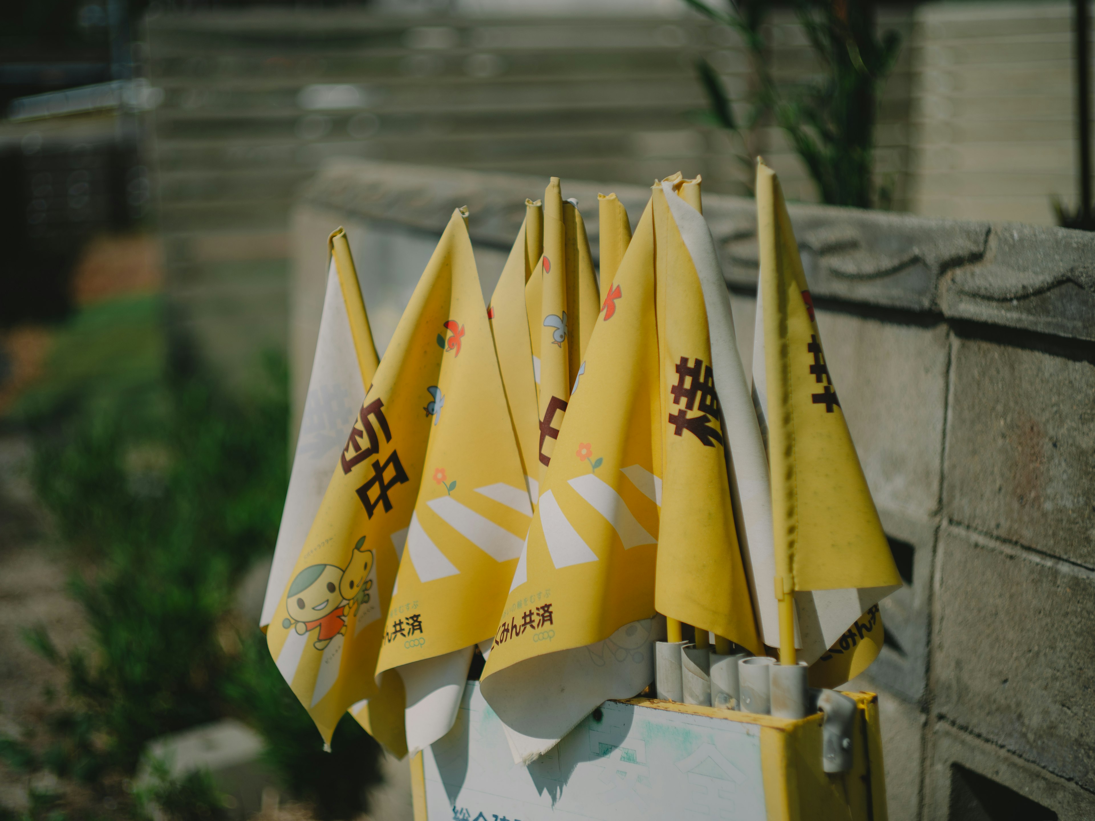 A collection of small yellow flags with text displayed in a garden setting