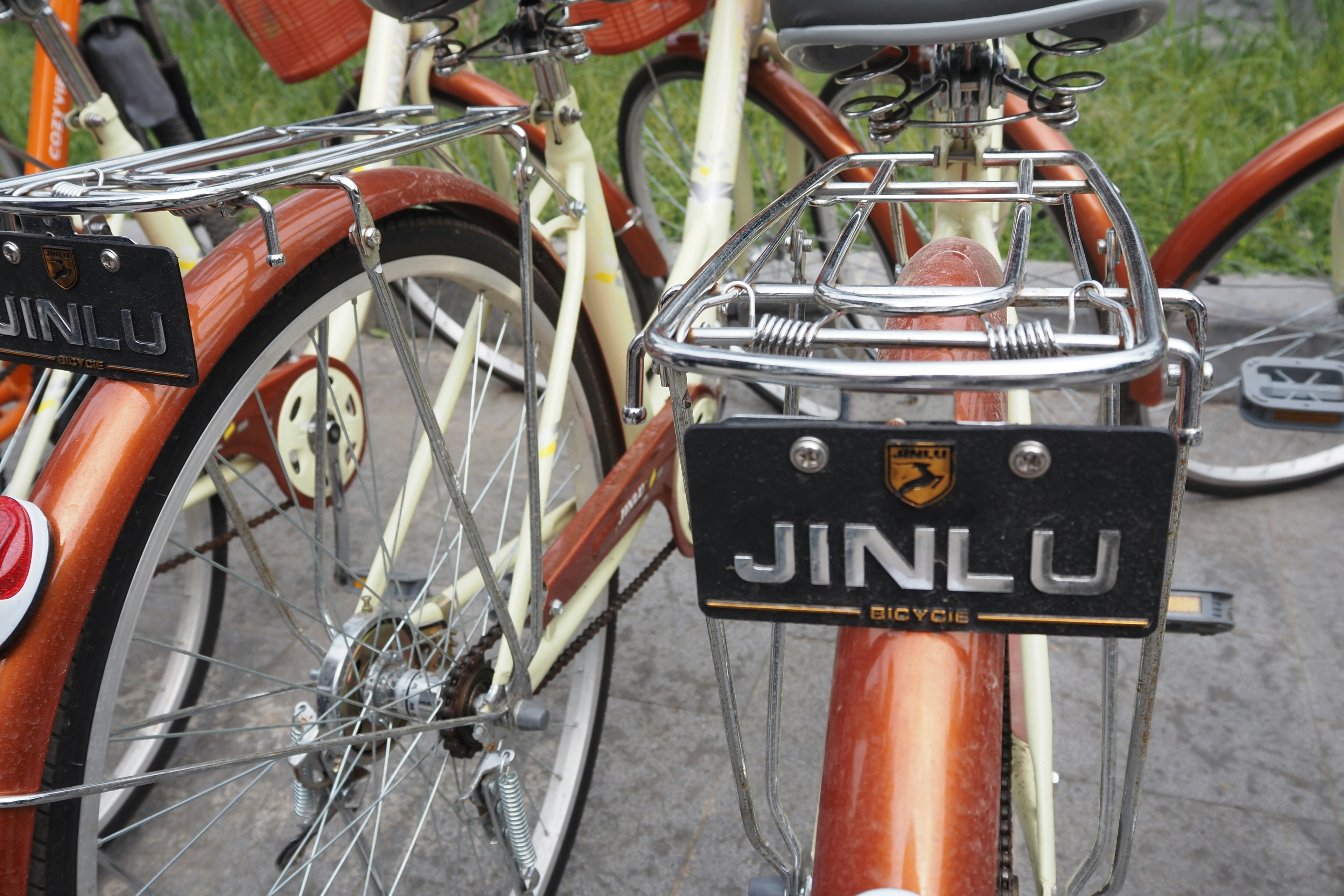 茶色の自転車のフレームに黒いプレートに「JINLU」と書かれている