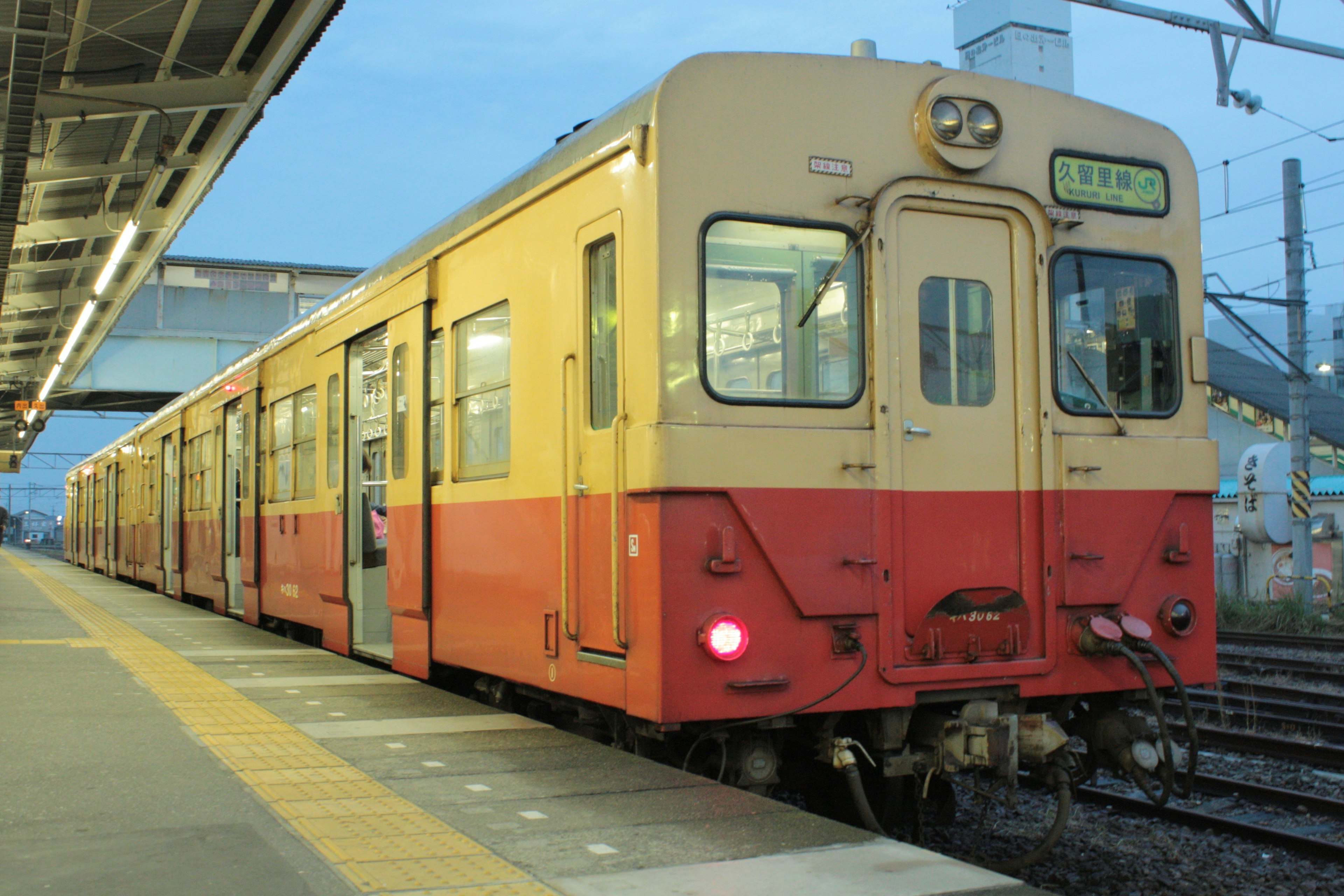 夕暮れ時の駅に停車中のオレンジとクリーム色の電車