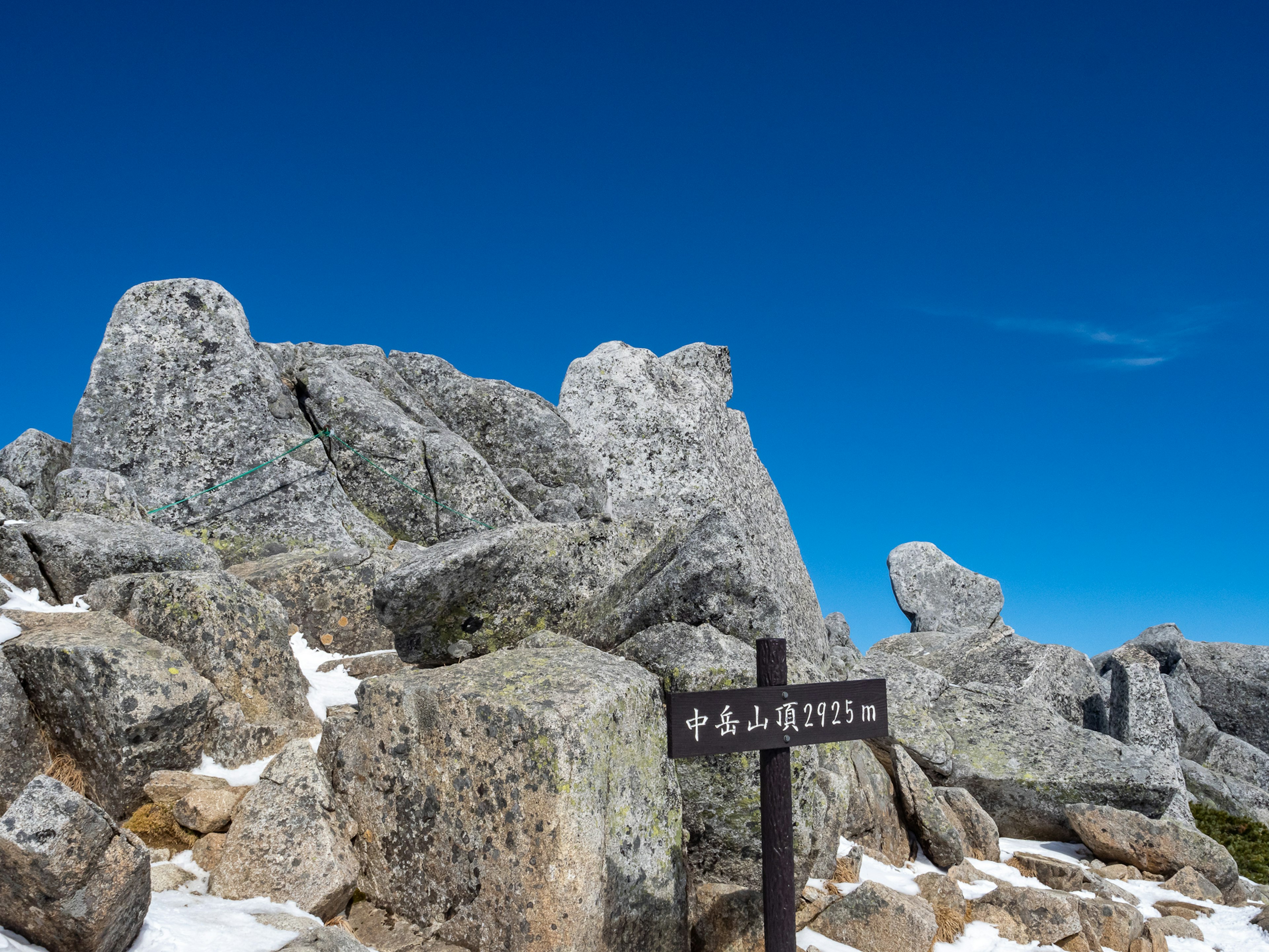 Paysage montagneux rocheux sous un ciel bleu avec un panneau