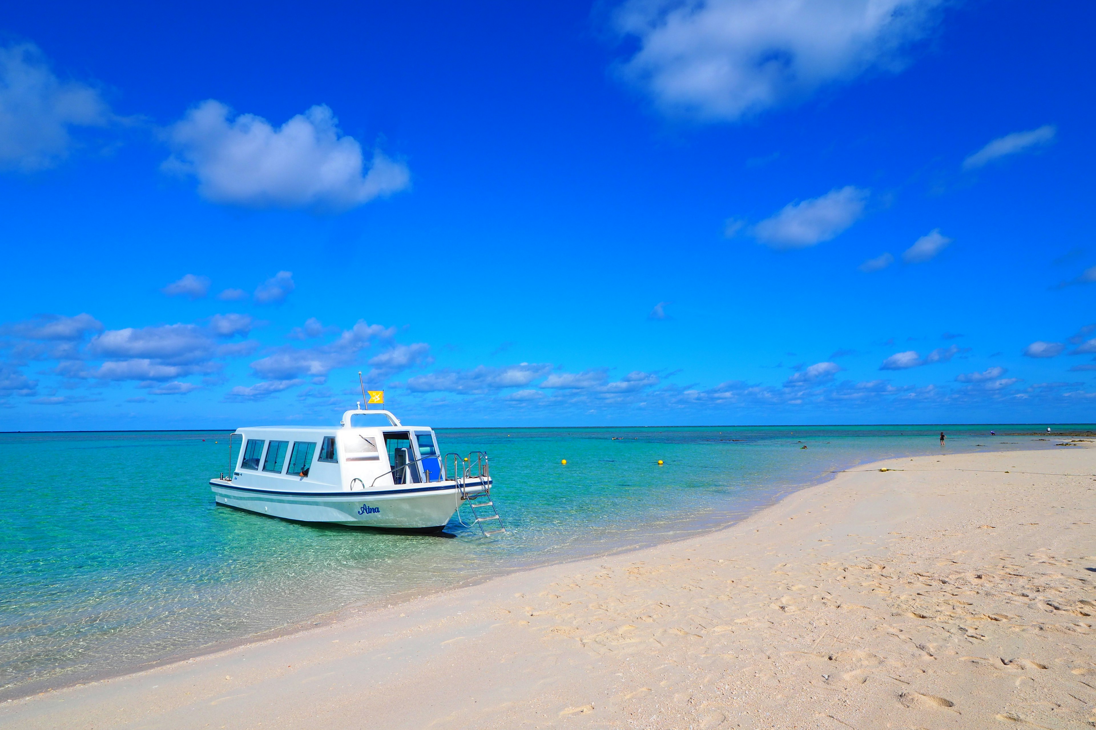 Weißes Boot, das an einem Sandstrand unter einem blauen Himmel ankert