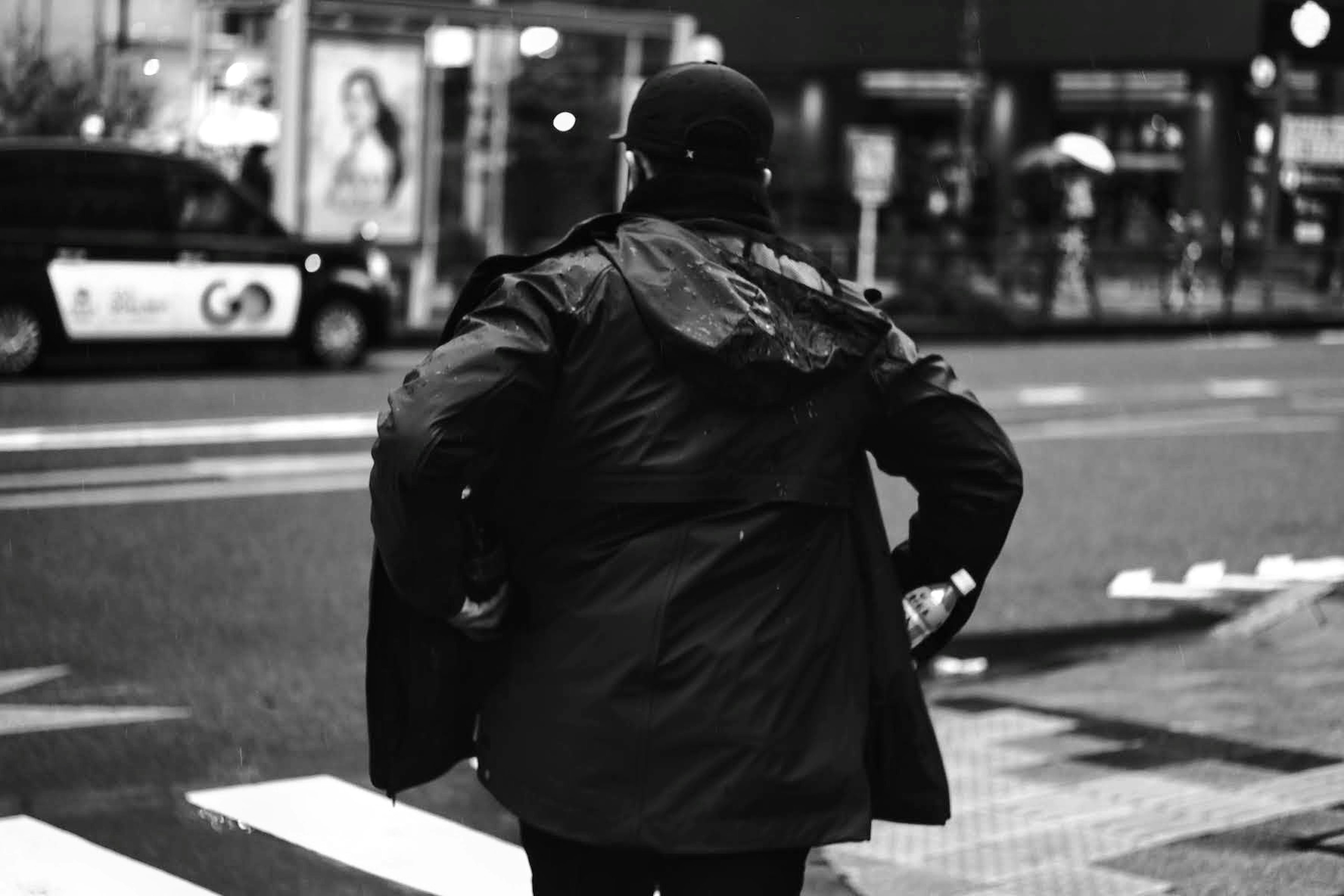 黒いコートを着た男性が横断歩道を渡っている都市の風景