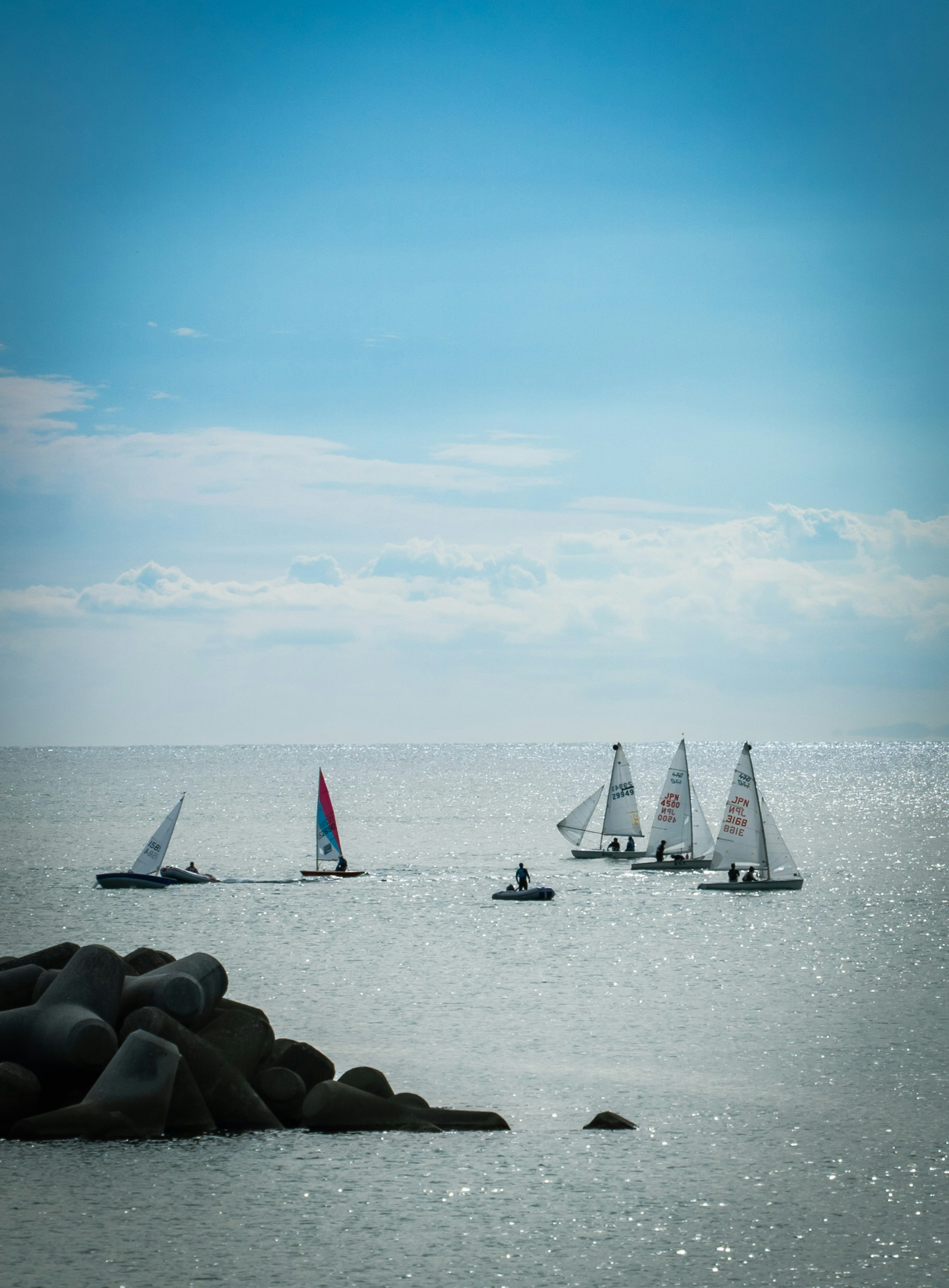 Sailing boats on a calm sea under a bright blue sky