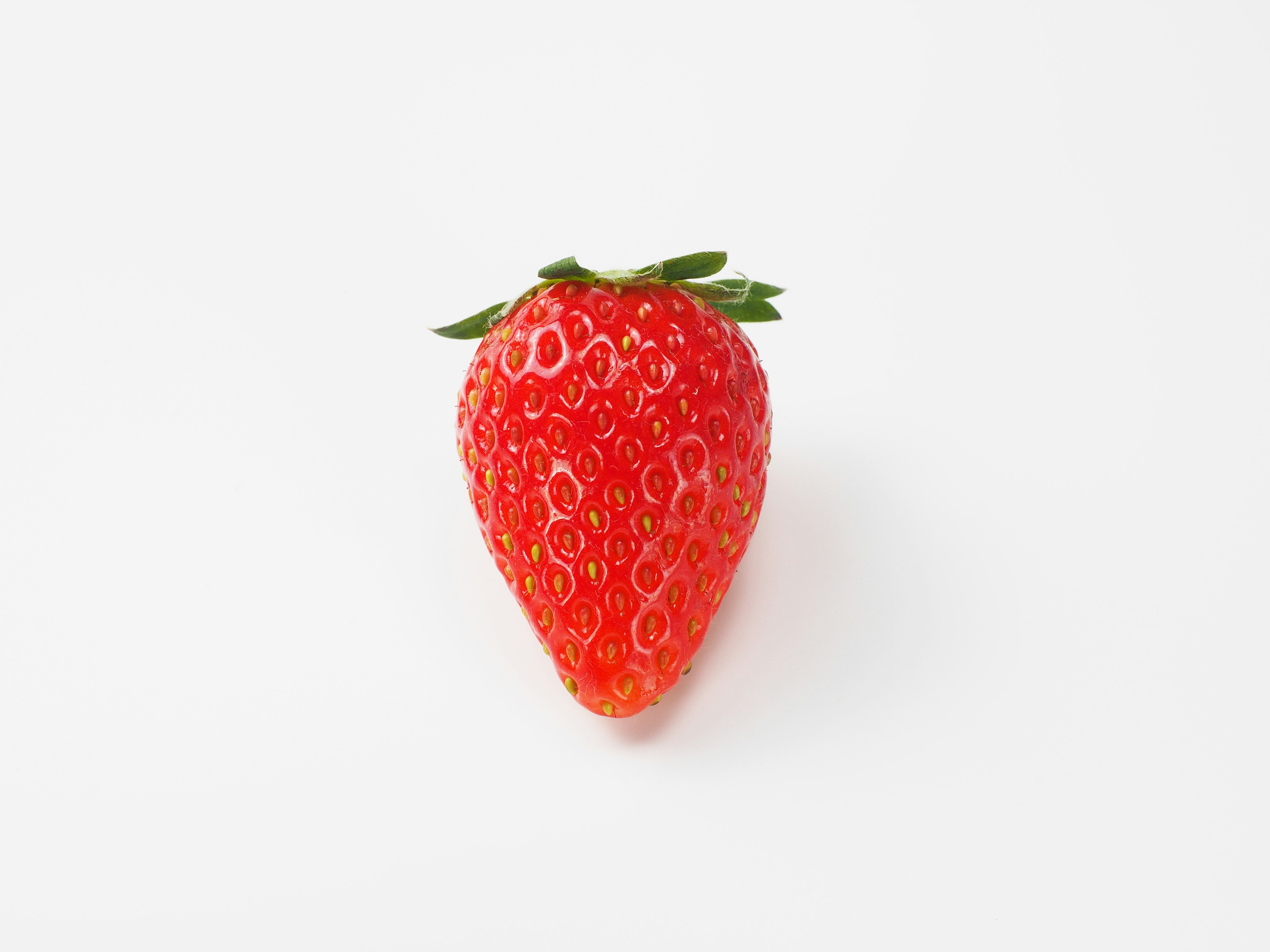 A vibrant red strawberry placed on a white background