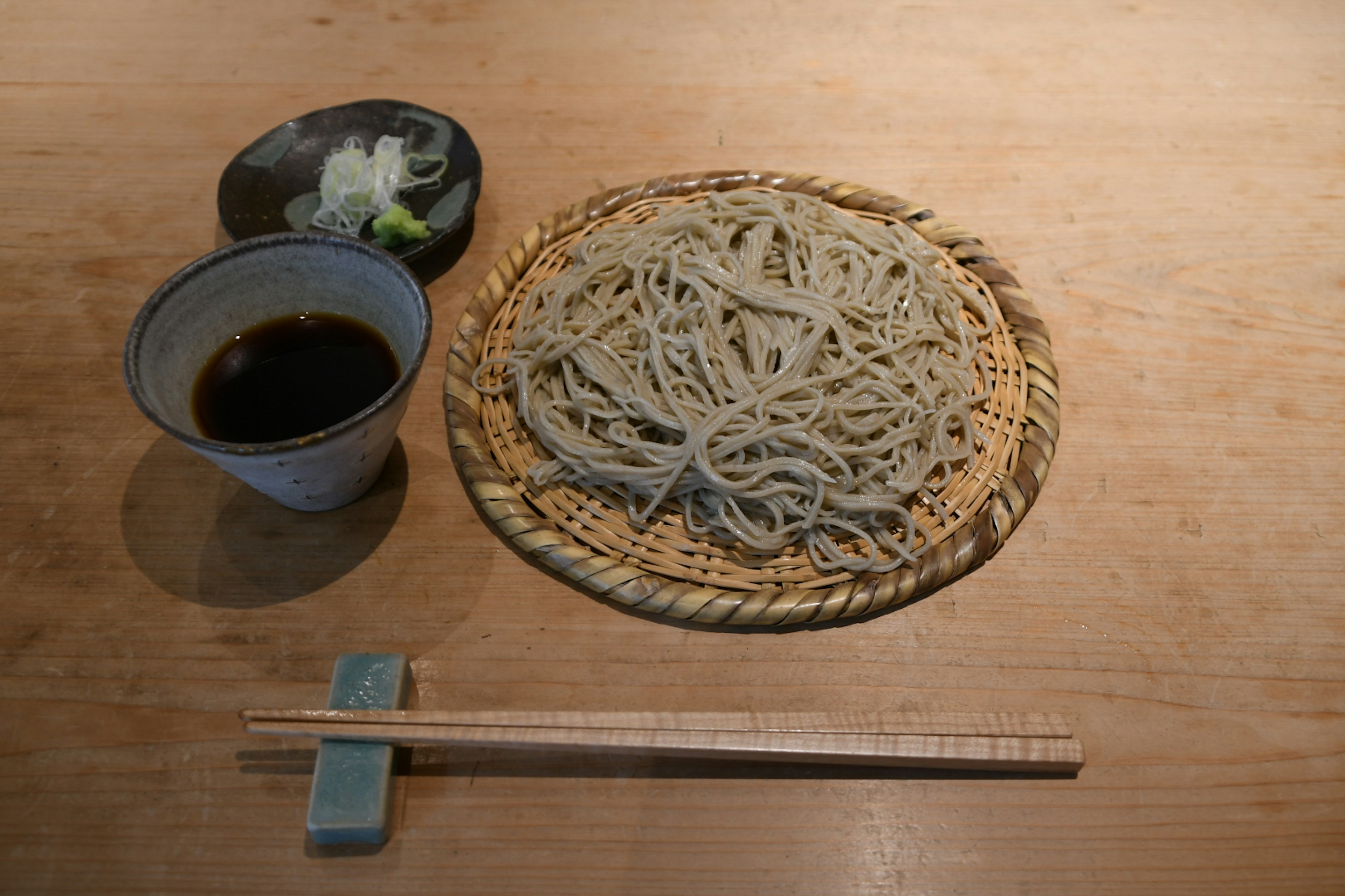 Plate of soba noodles with dipping sauce and green onion garnish