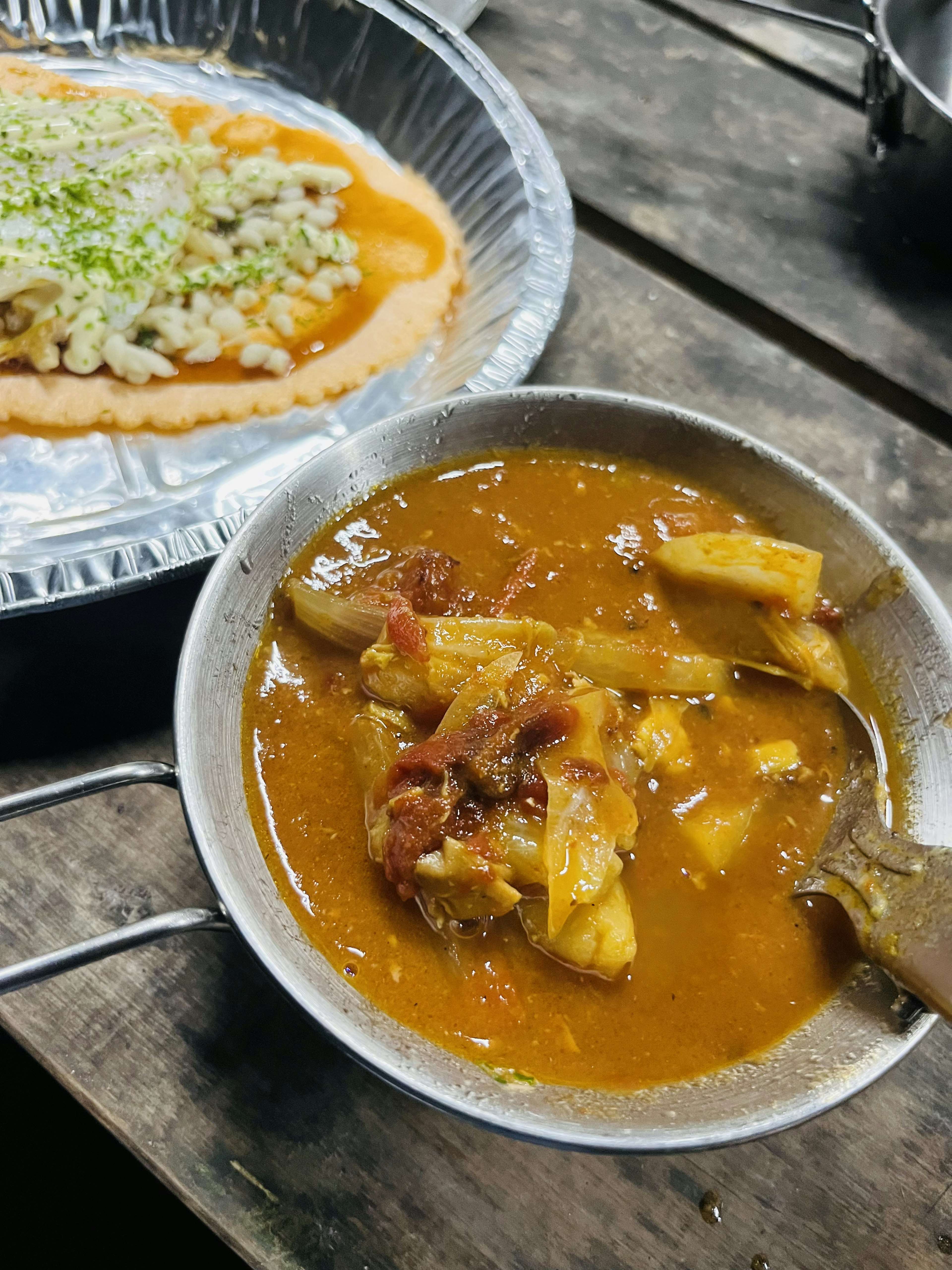 Un bol de plat au style curry avec des morceaux de viande et de légumes à côté d'une assiette de salade