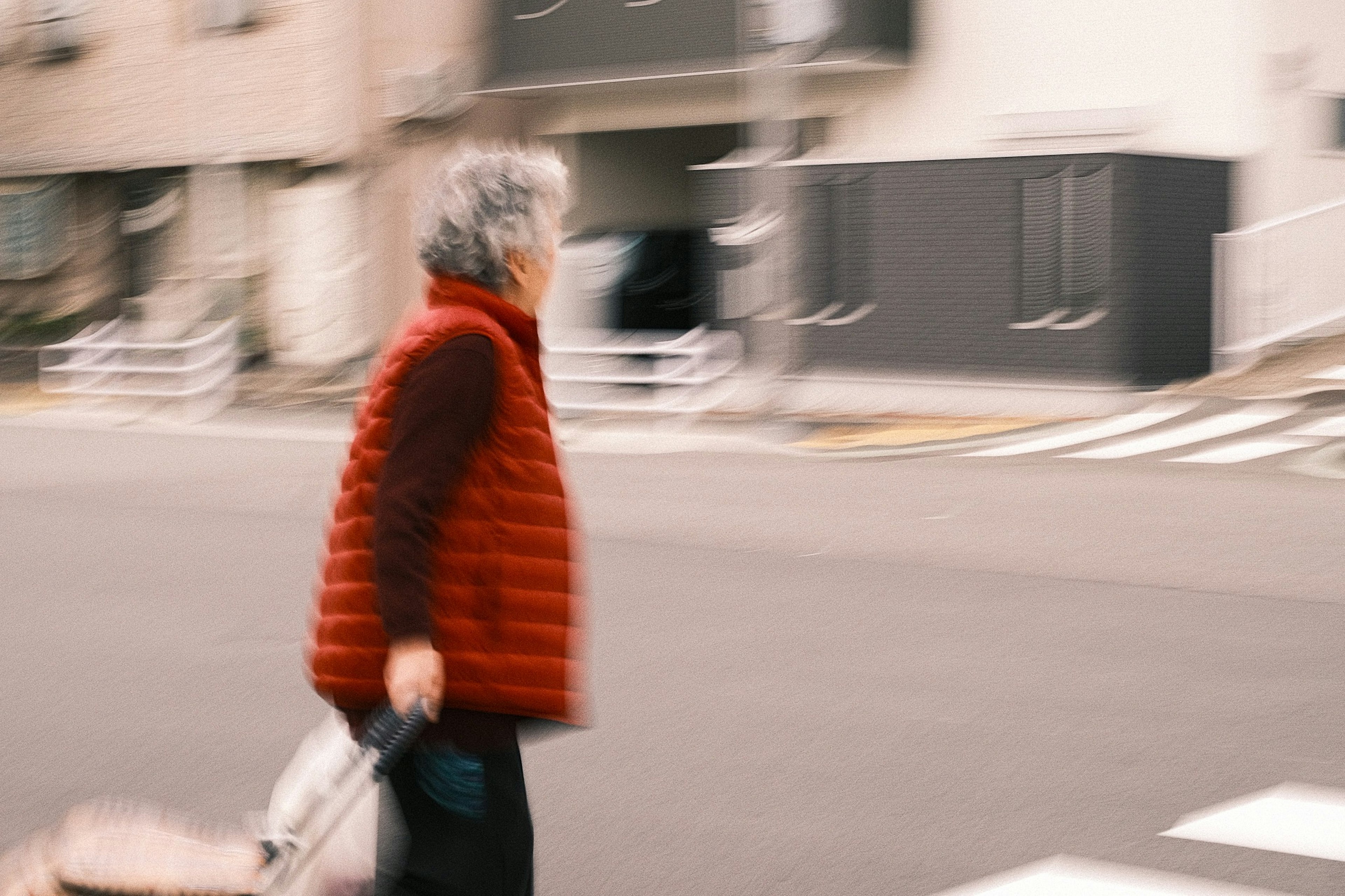 Femme âgée en gilet rouge traversant la rue