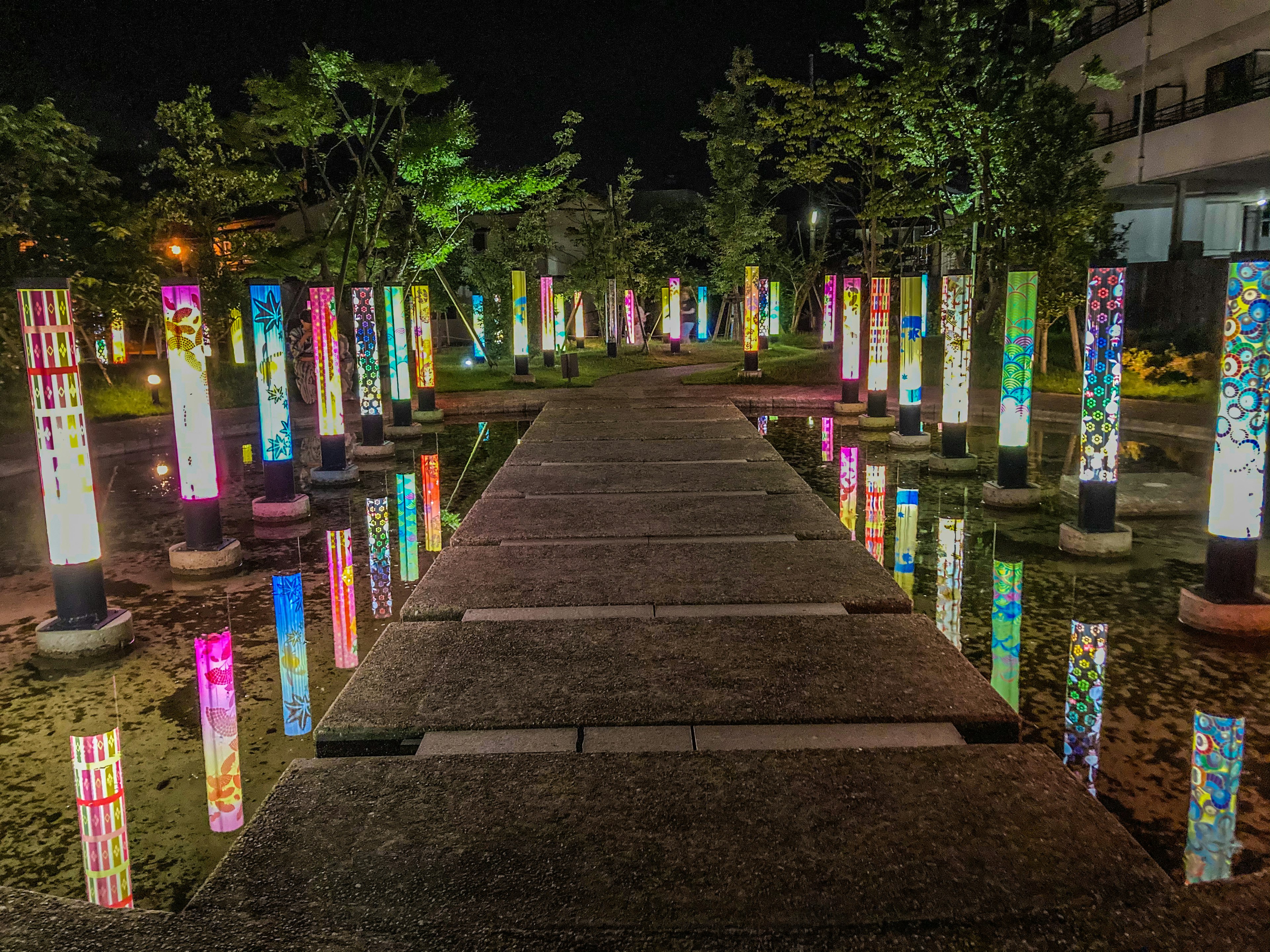 Illuminated columns lining a stone pathway in a night park