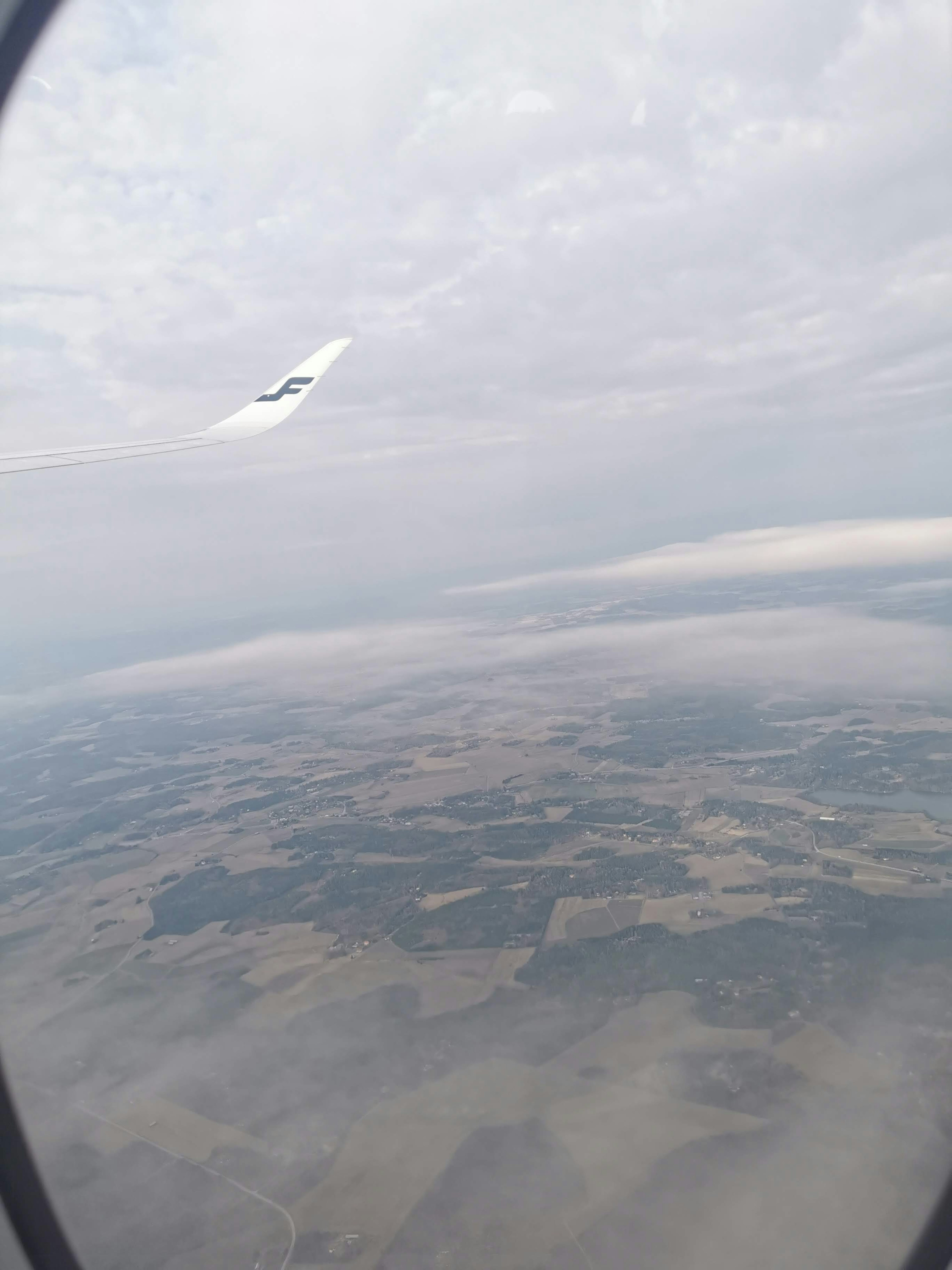 Vista desde una ventana de avión con cielo nublado y tierra abajo