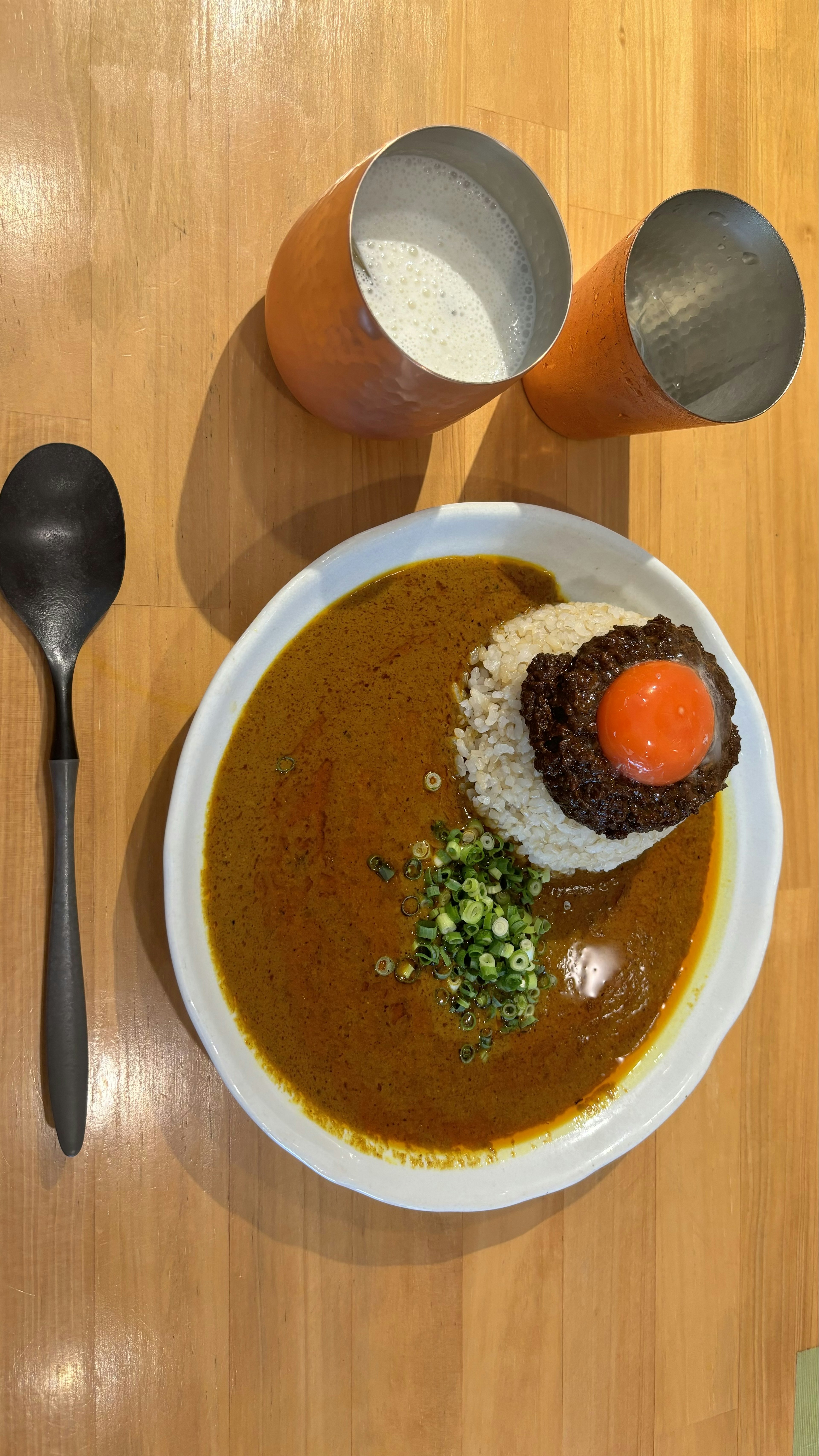 Piring nasi kari yang dihiasi dengan telur setengah matang dan daun bawang cincang