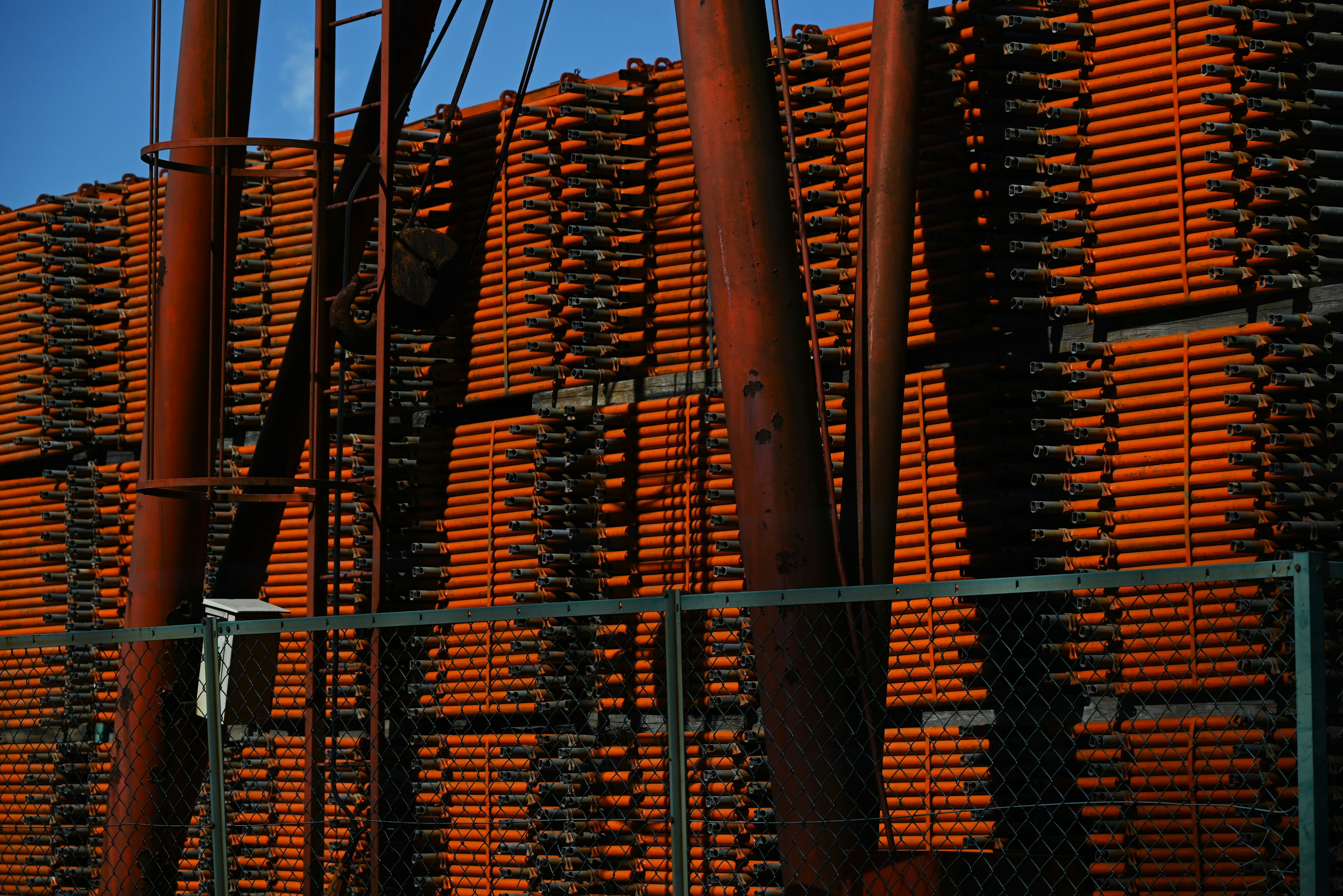 Materiales de construcción apilados en naranja con estructuras metálicas