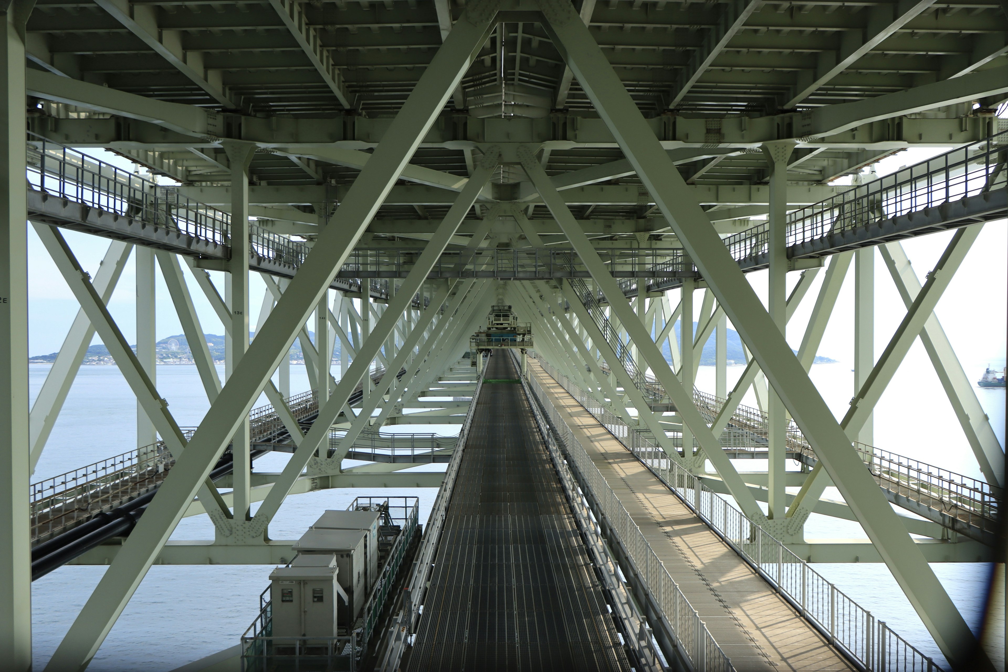 Photo d'une structure de pont vue de dessous avec des poutres en acier croisées et des voies