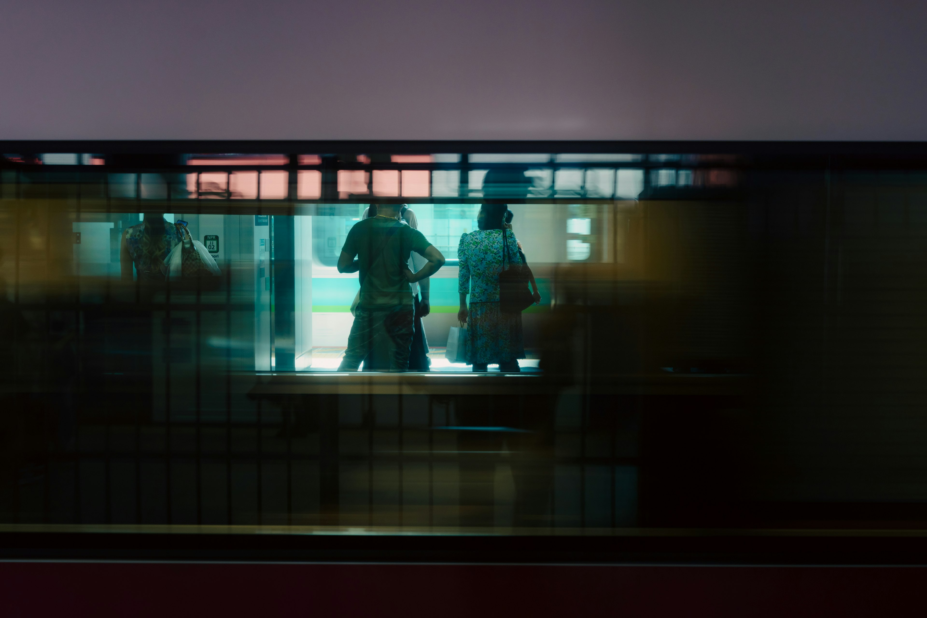 Silhouettes of people seen through a dimly lit room with contrasting colors