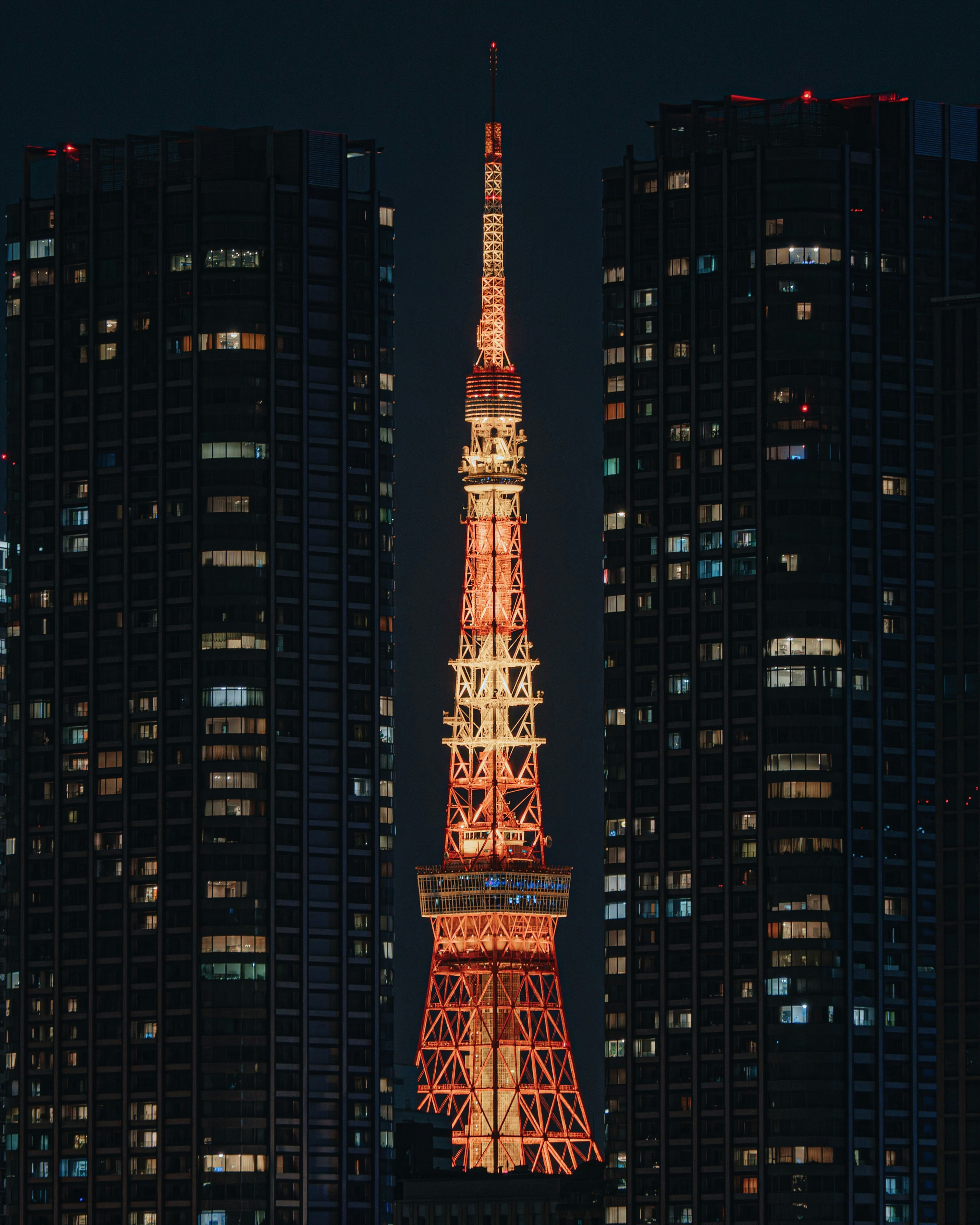 Tokyo Tower illuminated at night between skyscrapers