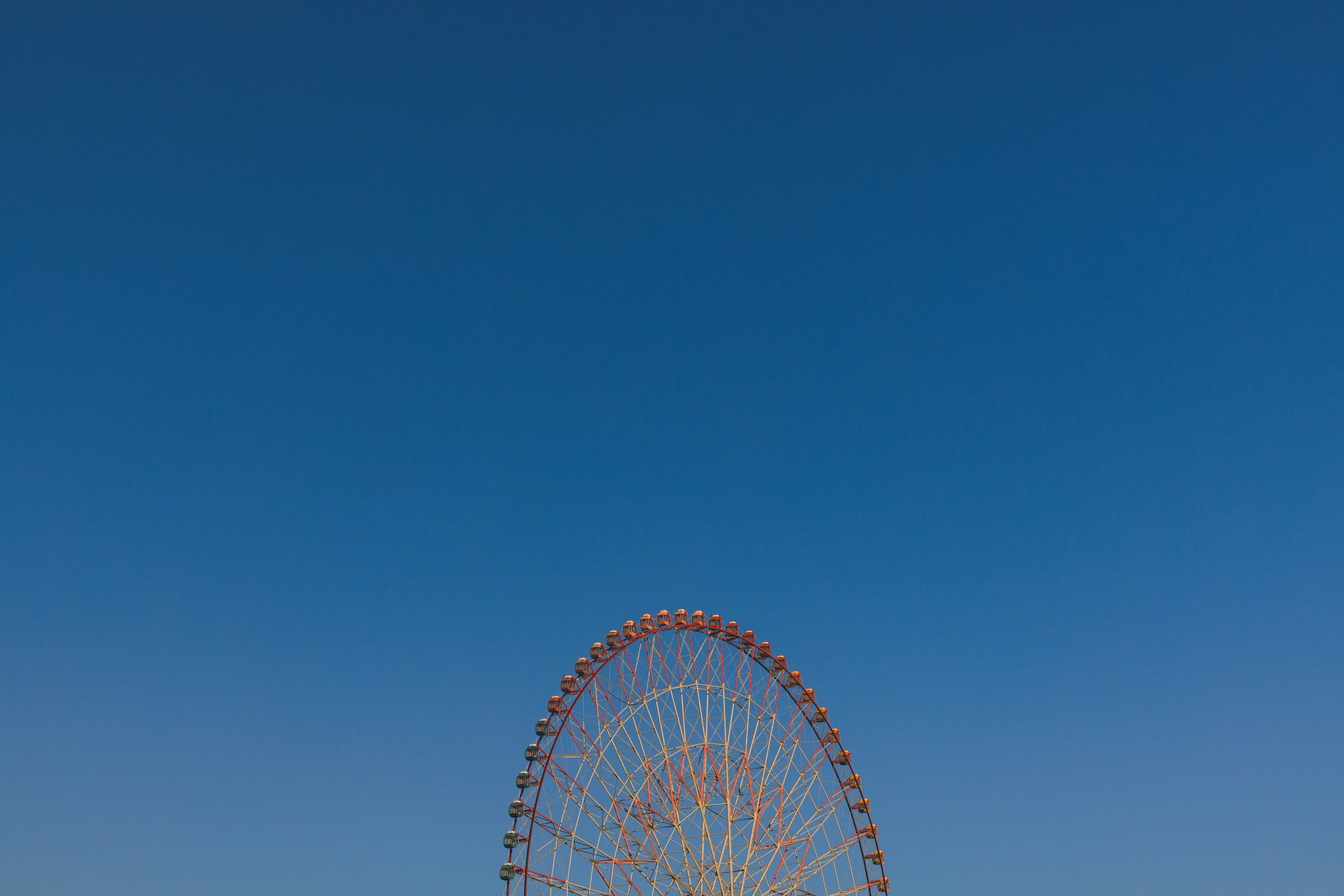 青い空の下にある大きな観覧車の上部