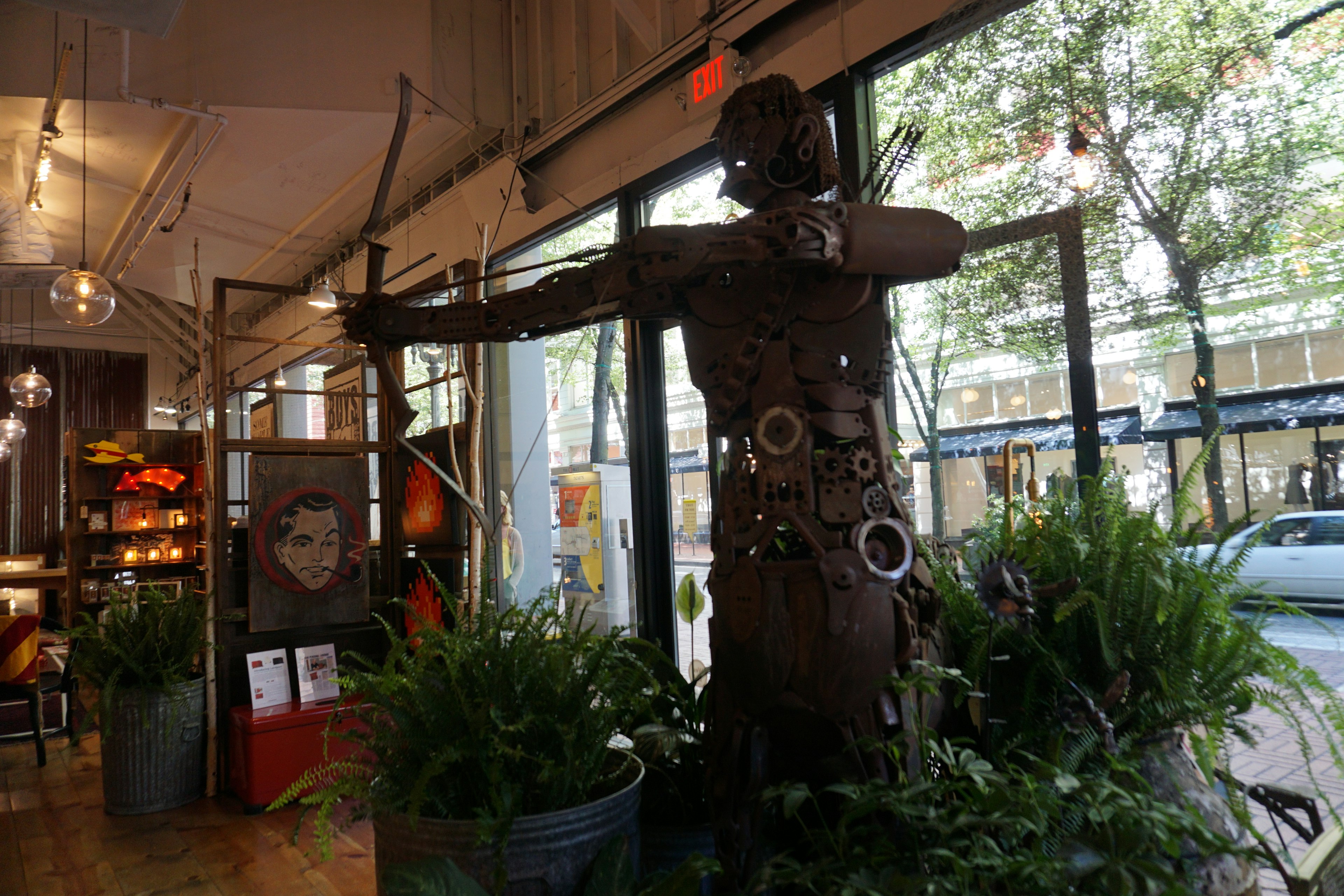 Escultura de un arquero de metal en un espacio interior rodeado de plantas