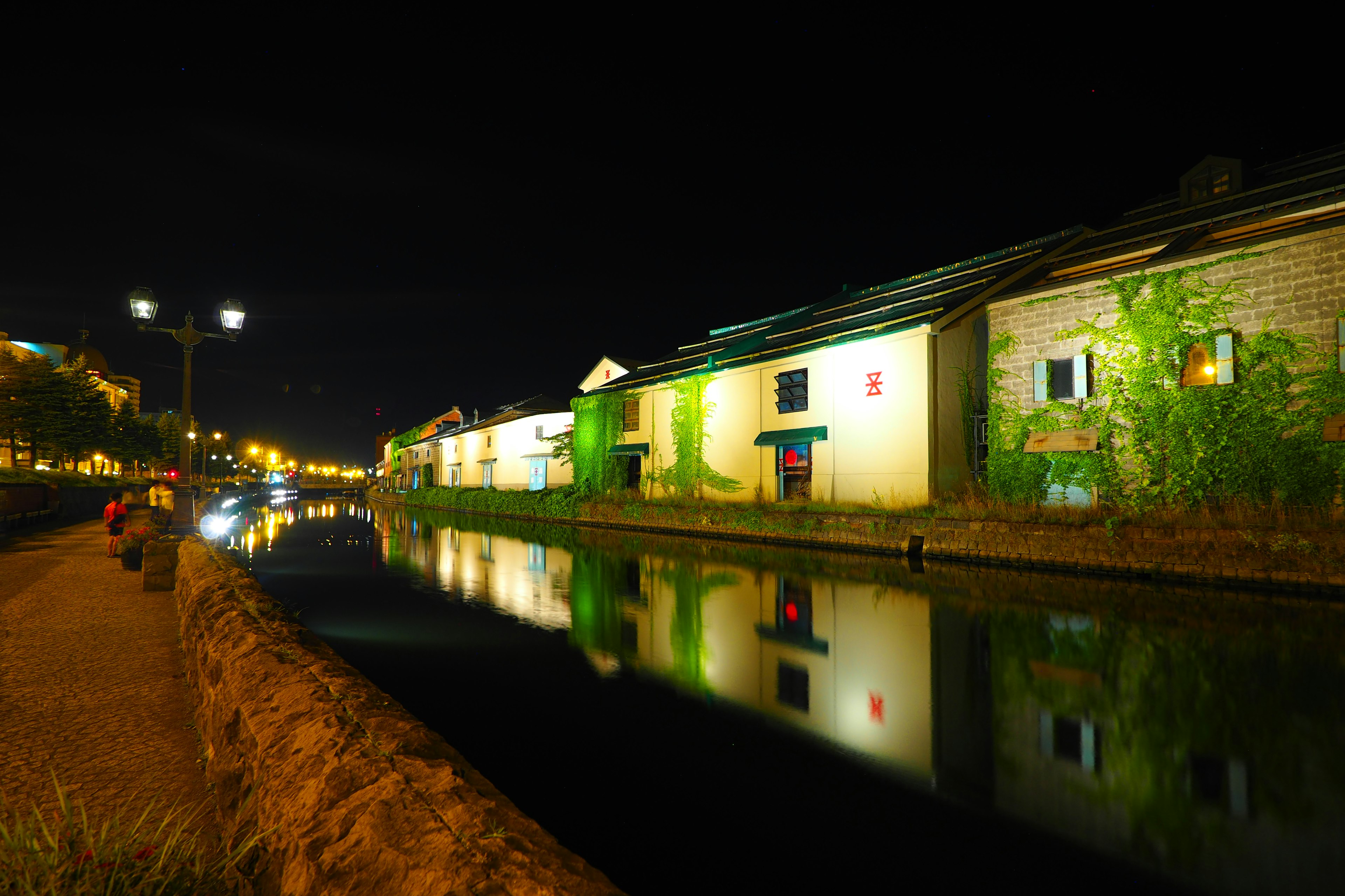 Pemandangan malam yang tenang dari kanal dengan pantulan bangunan dan lampu jalan