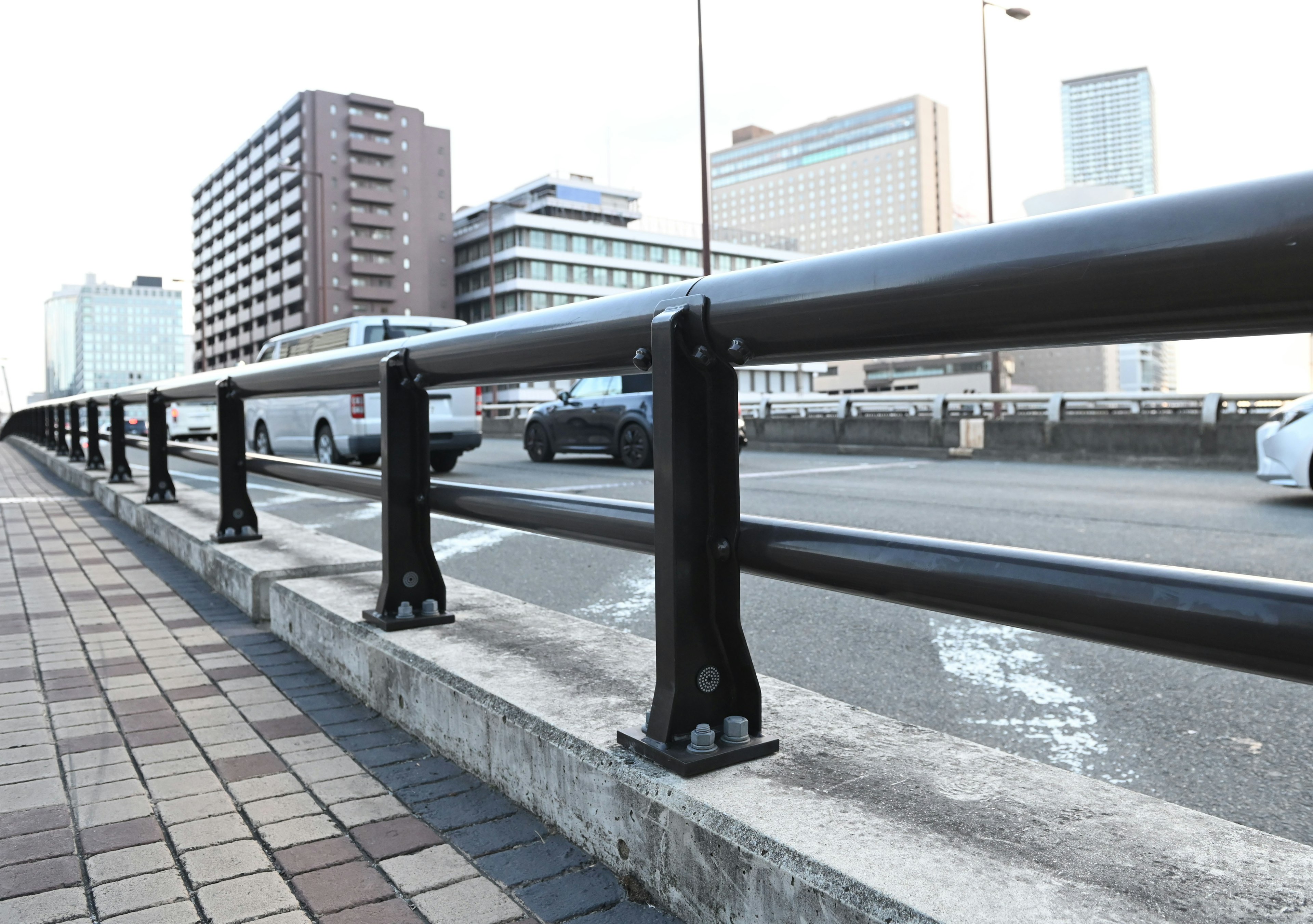 Urban scene featuring a black railing alongside a paved walkway