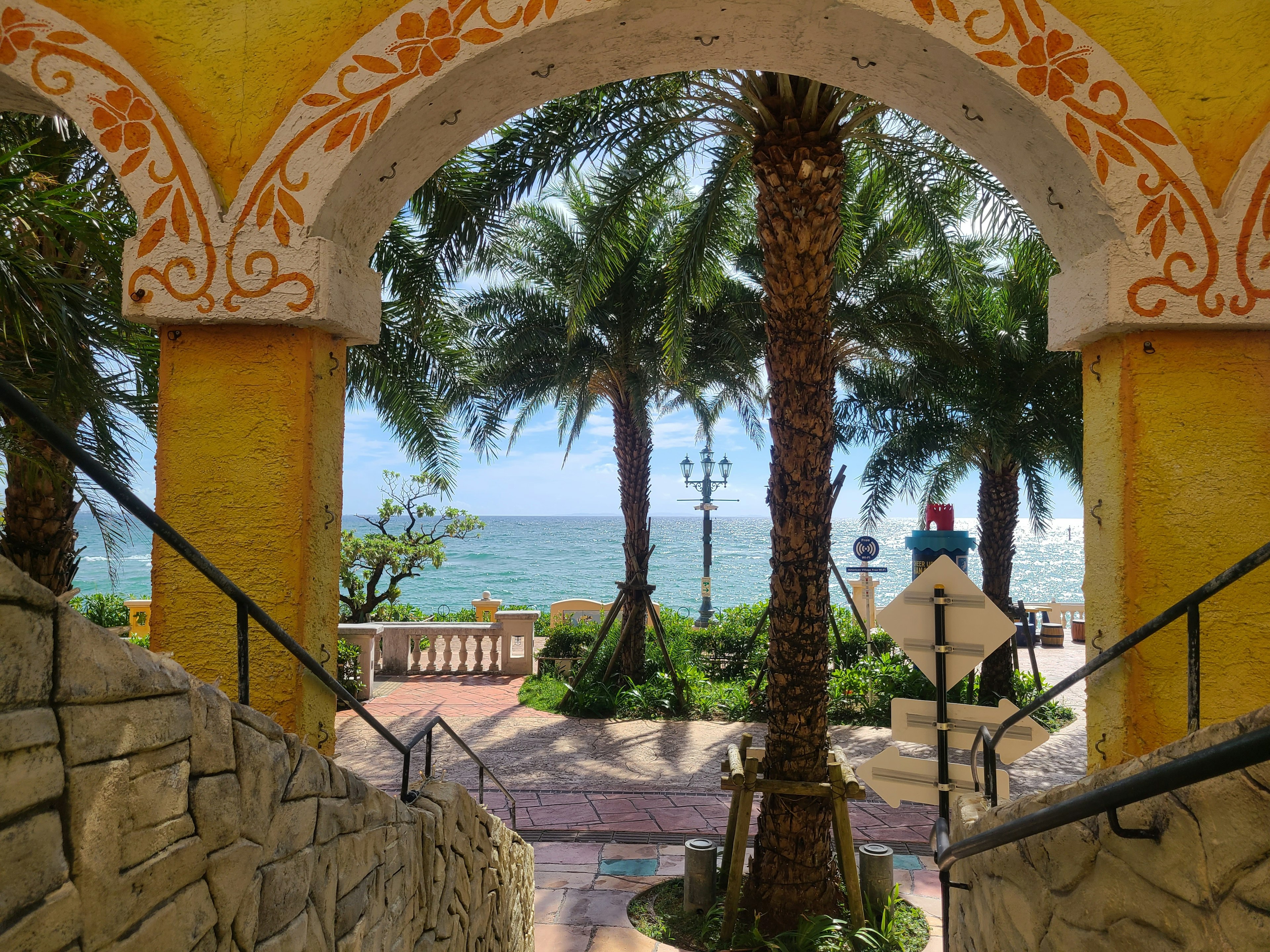 View of the ocean and palm trees through a yellow archway