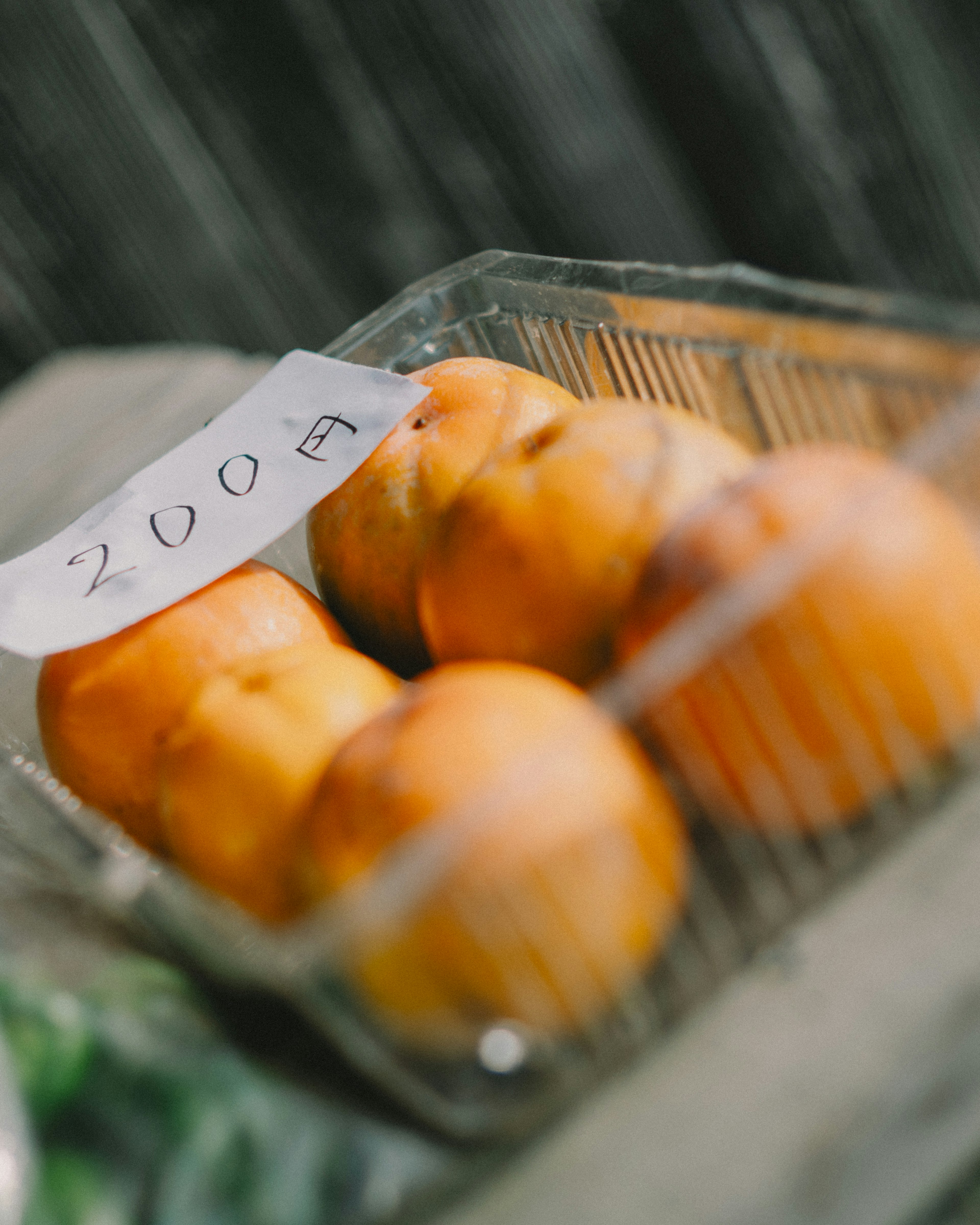 A clear plastic container holding orange peaches with the number 2009