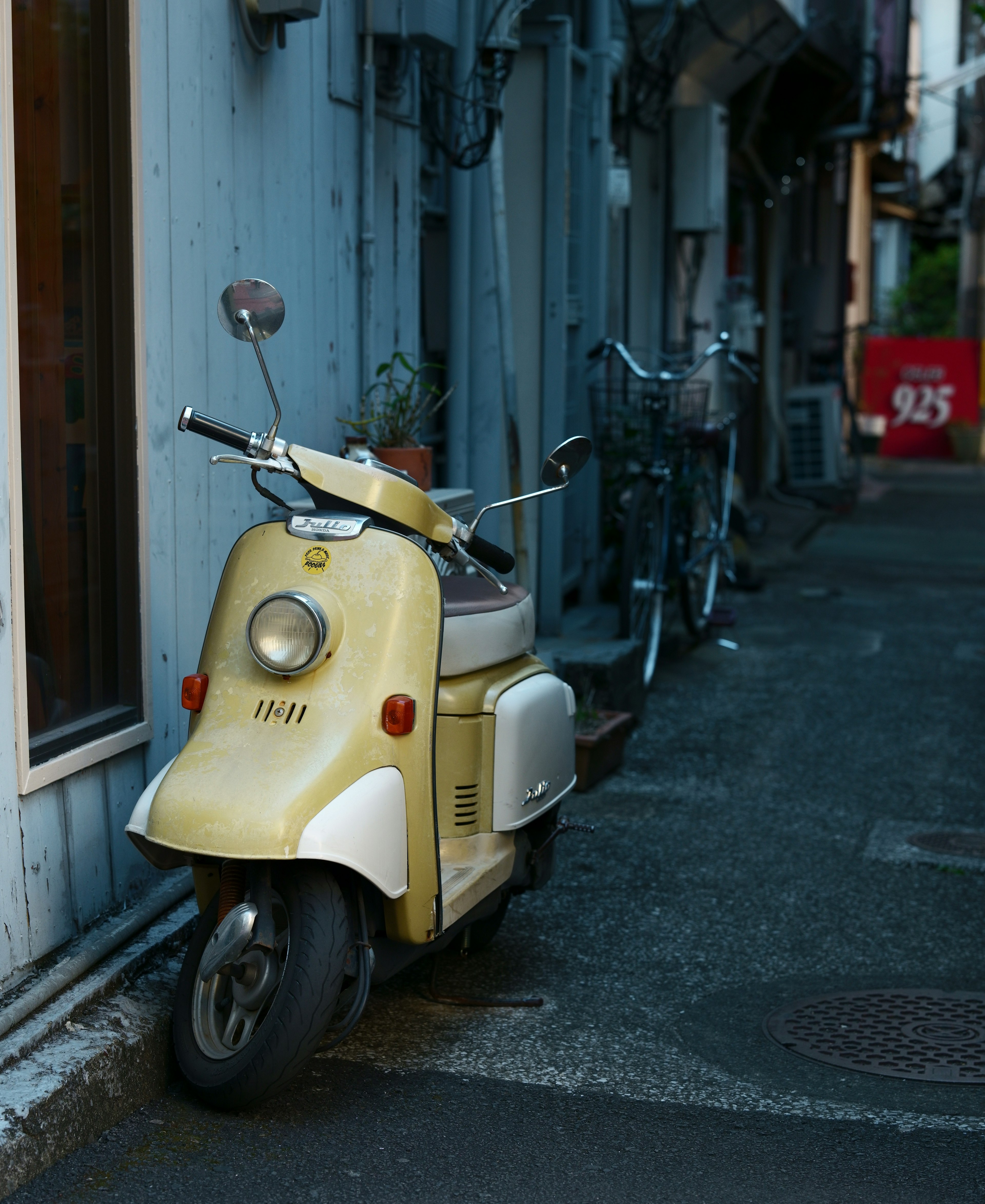 Une ruelle étroite avec un scooter jaune garé à côté de bicyclettes