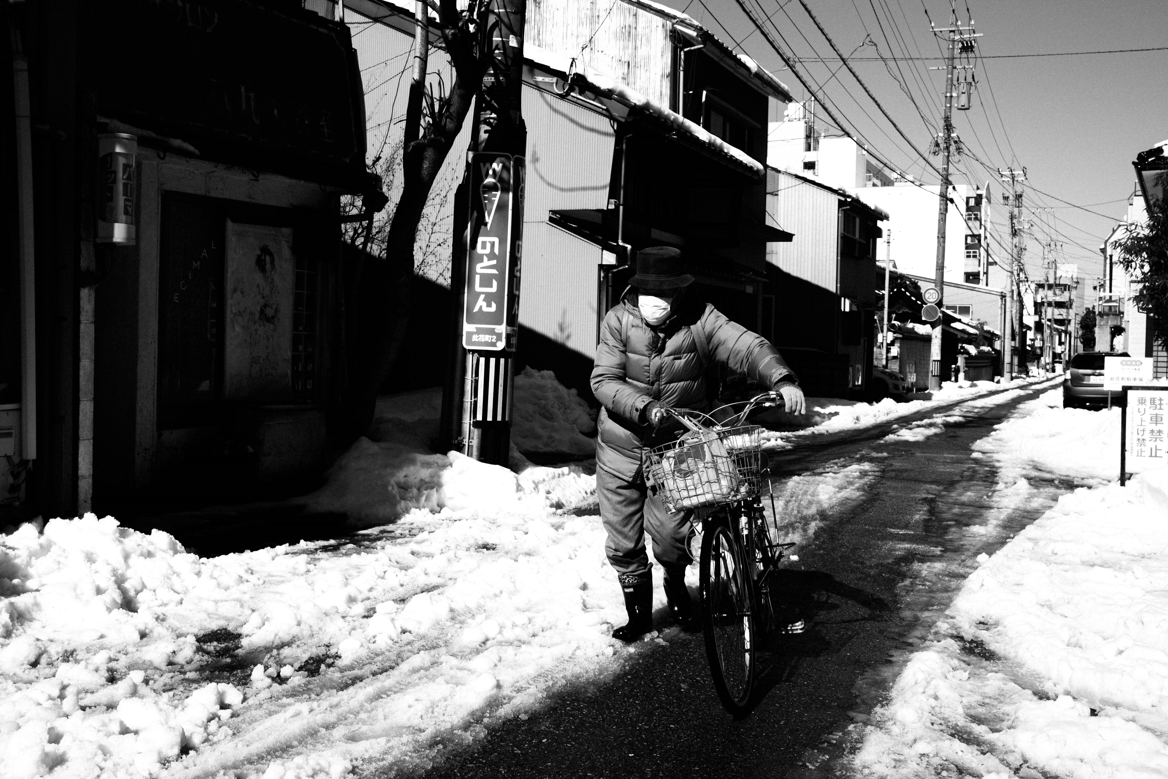 騎自行車的人在雪覆蓋的街道上