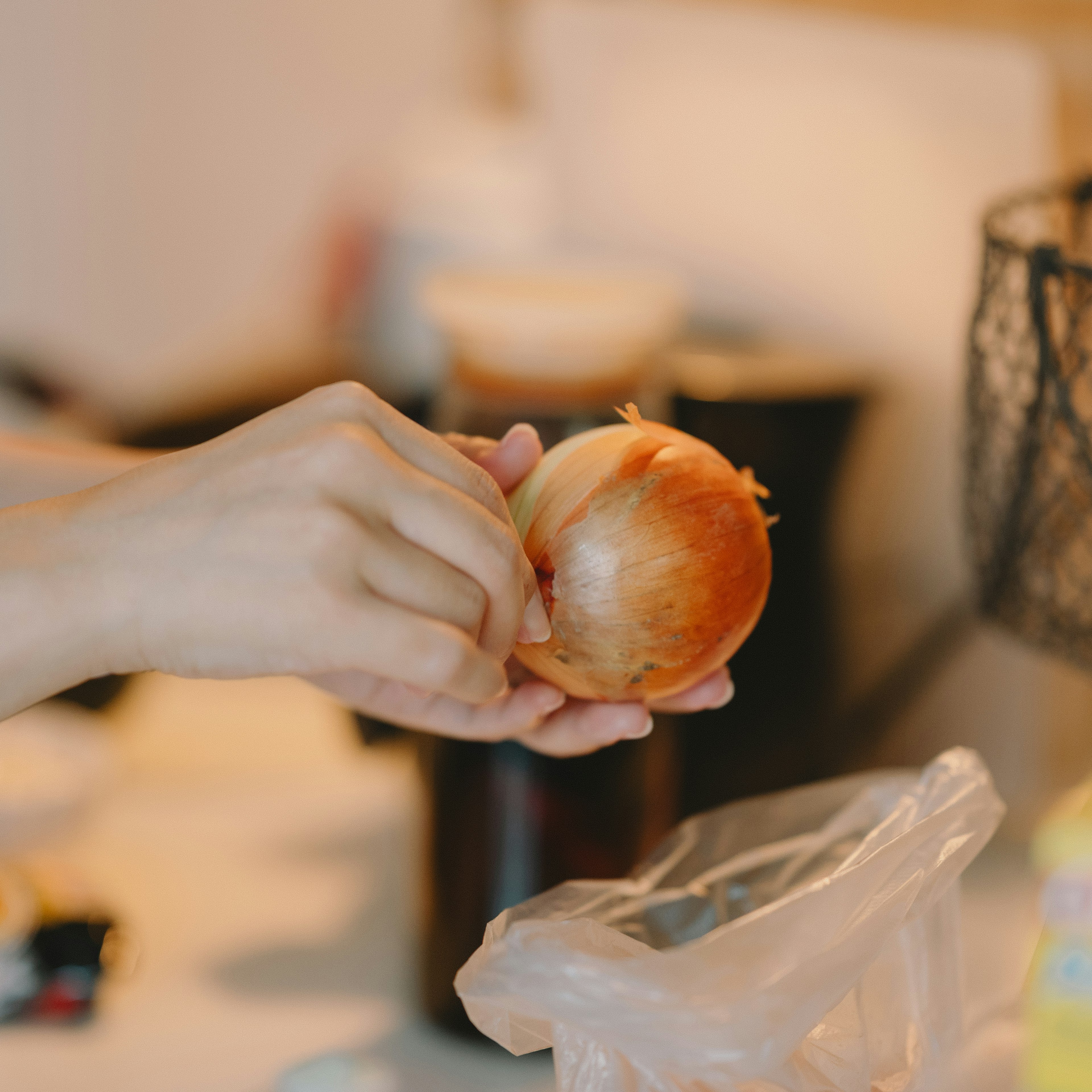 Person hält eine Zwiebel und schält sie