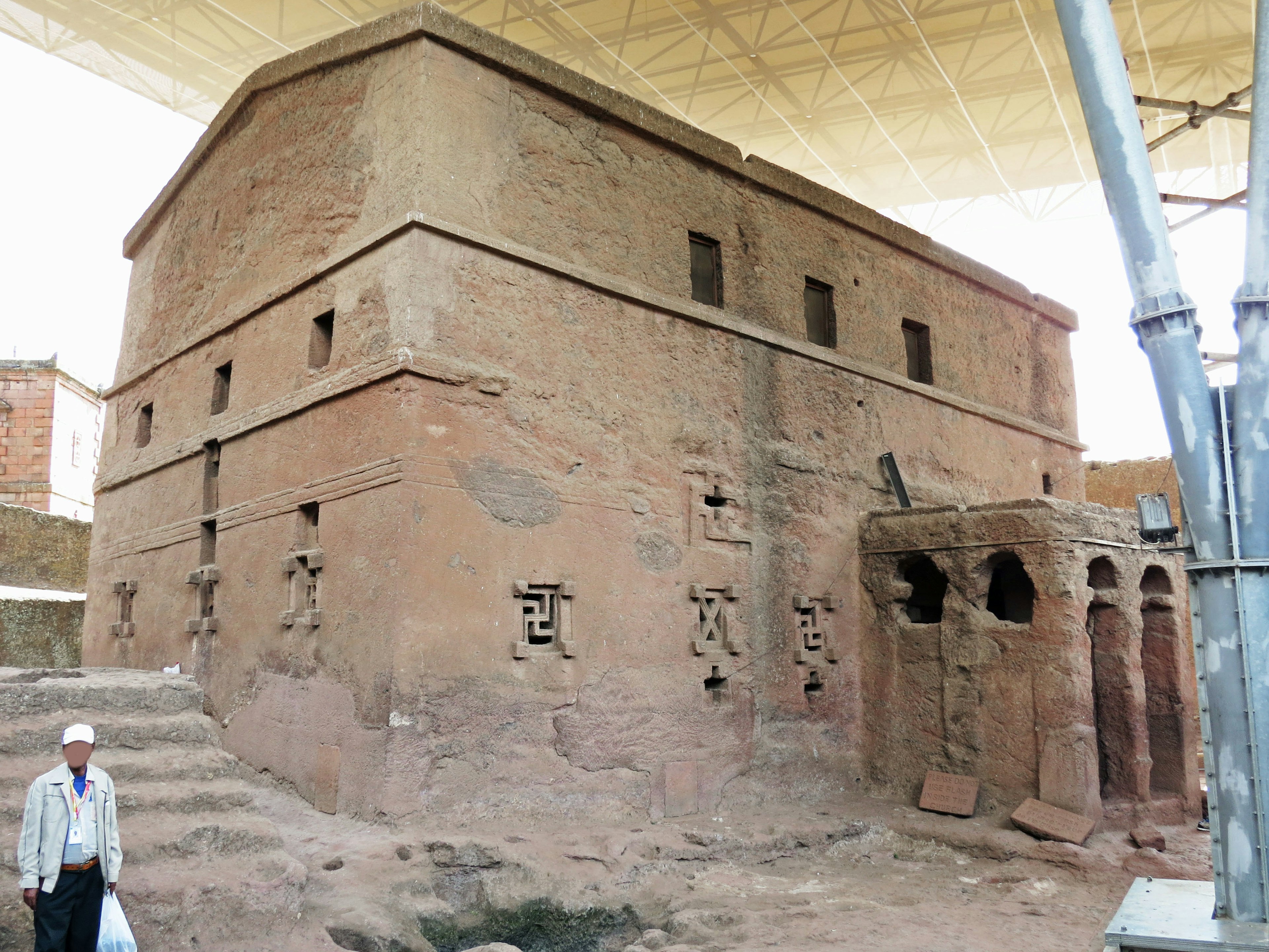 Ancienne structure en terre sous un toit protecteur présentant des sculptures complexes