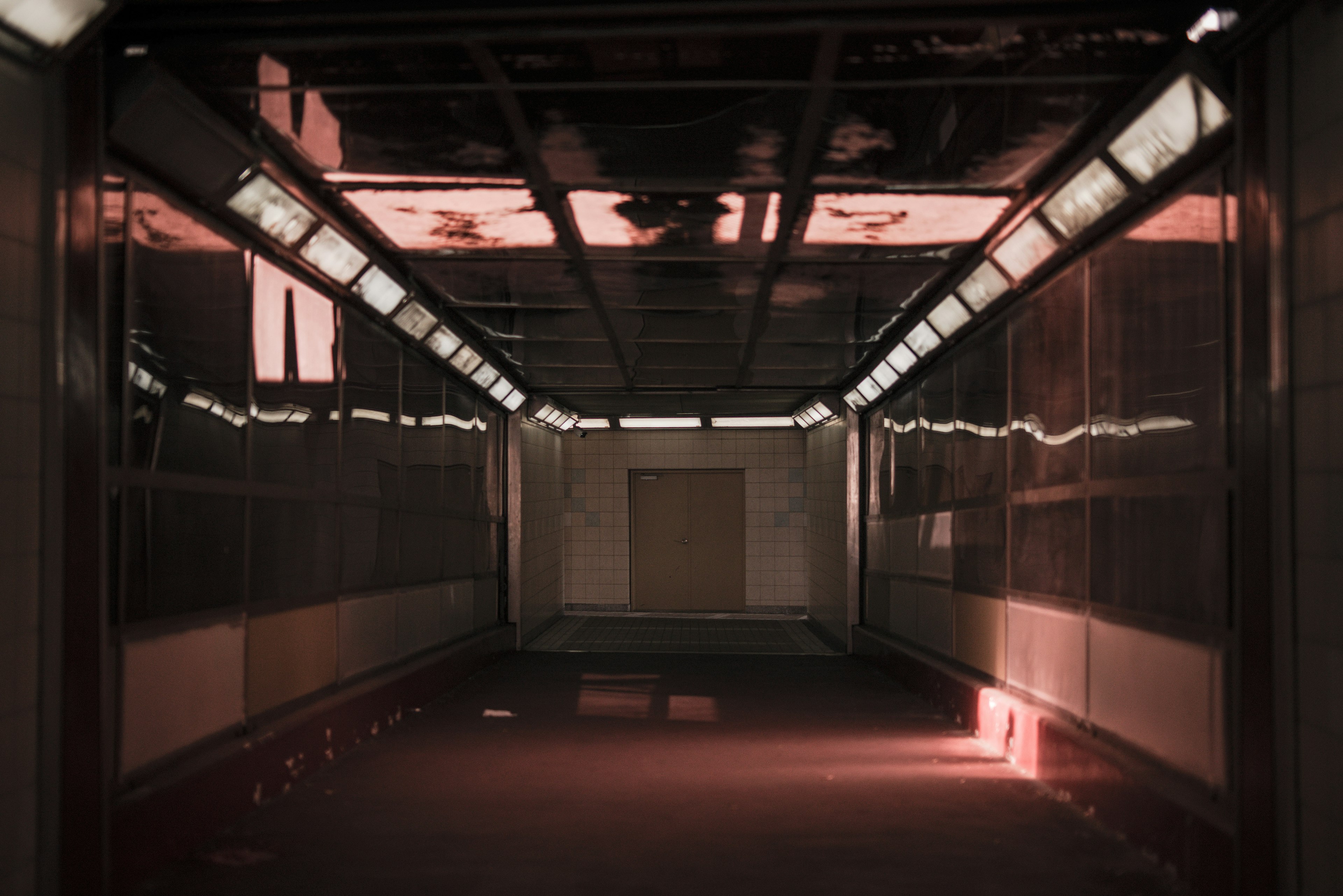 Interior of a dimly lit corridor with reflective walls and ceiling lights