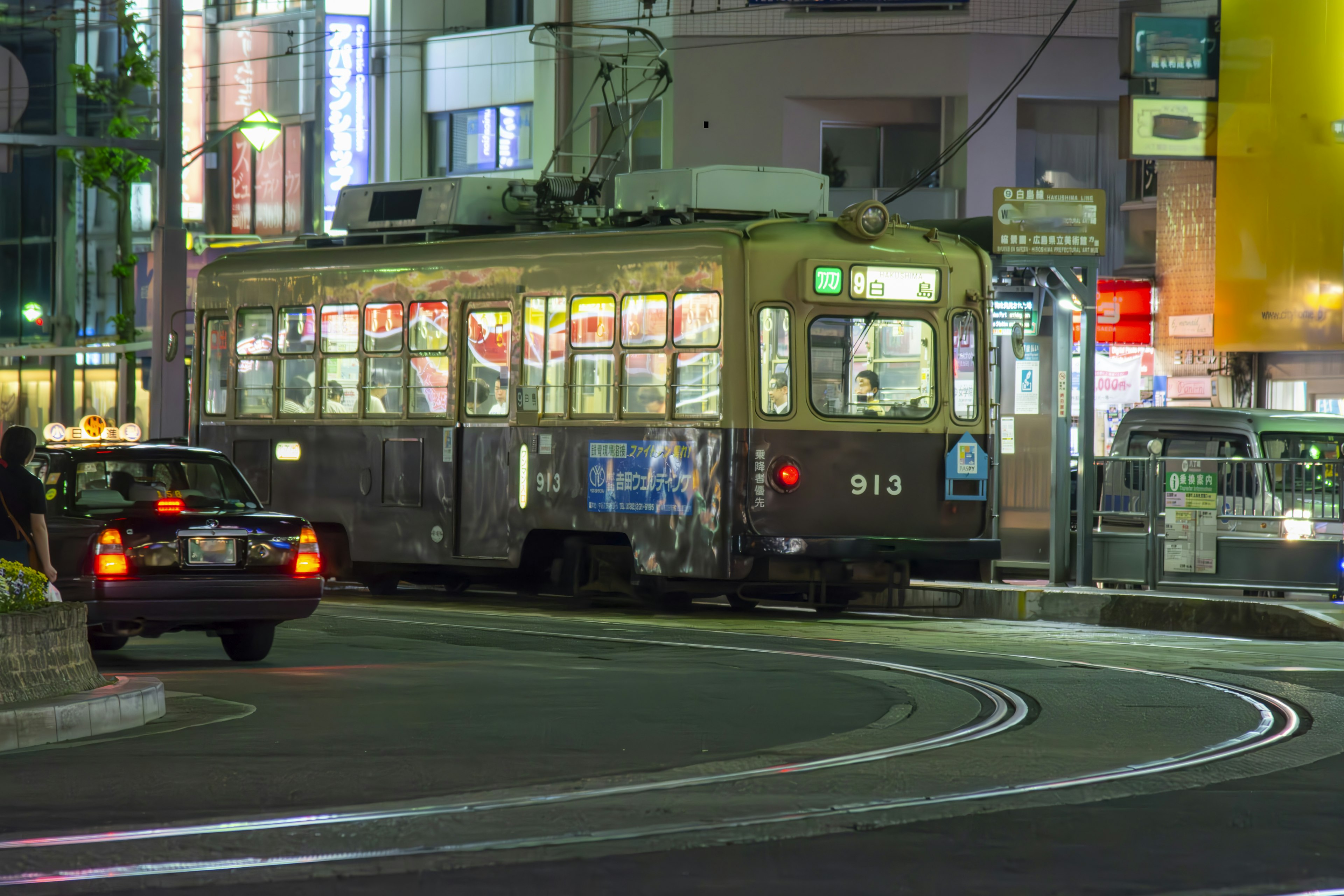 夜の街角に停車する古い路面電車とタクシー