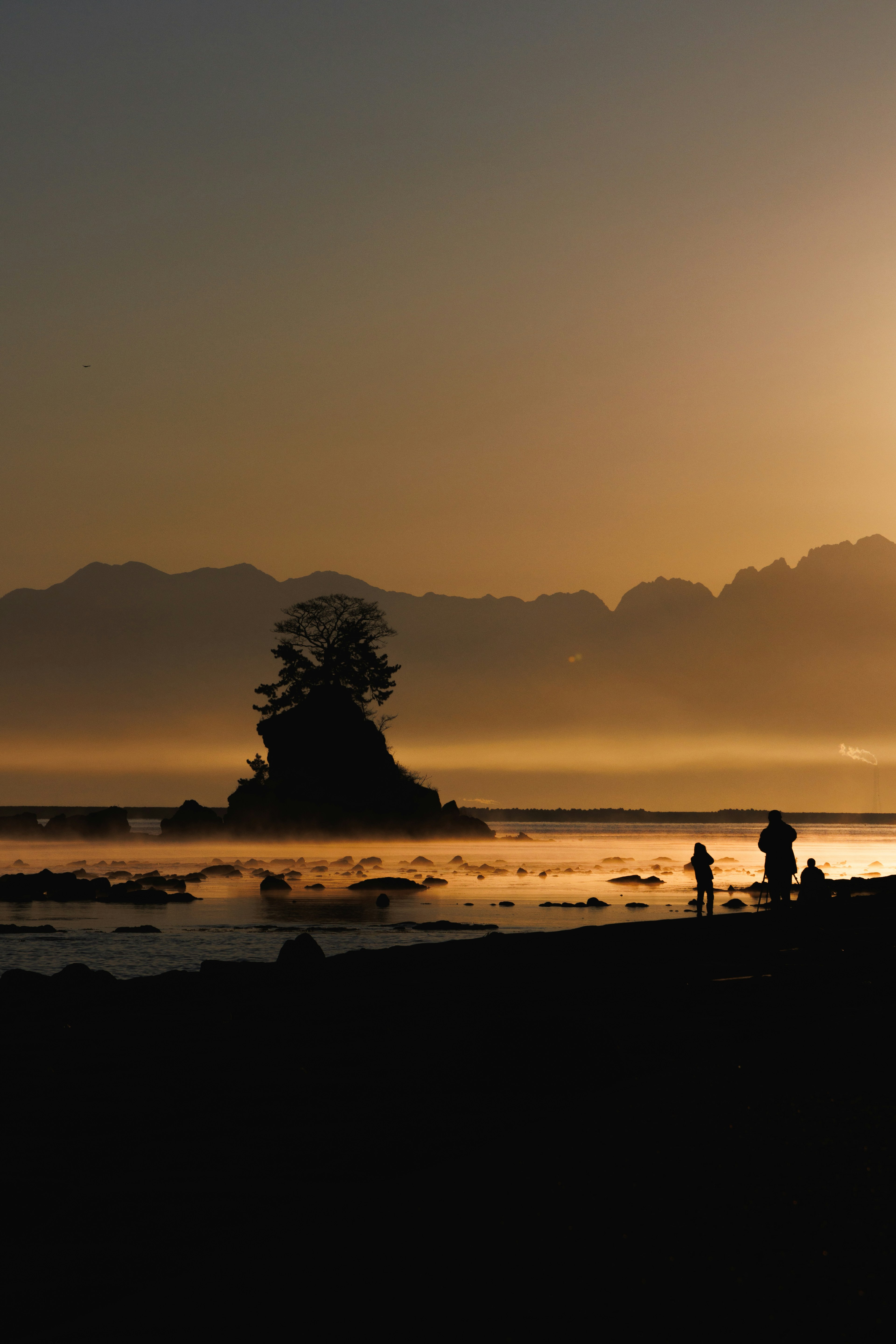 Silhouette of people and a small island at sunset on the beach