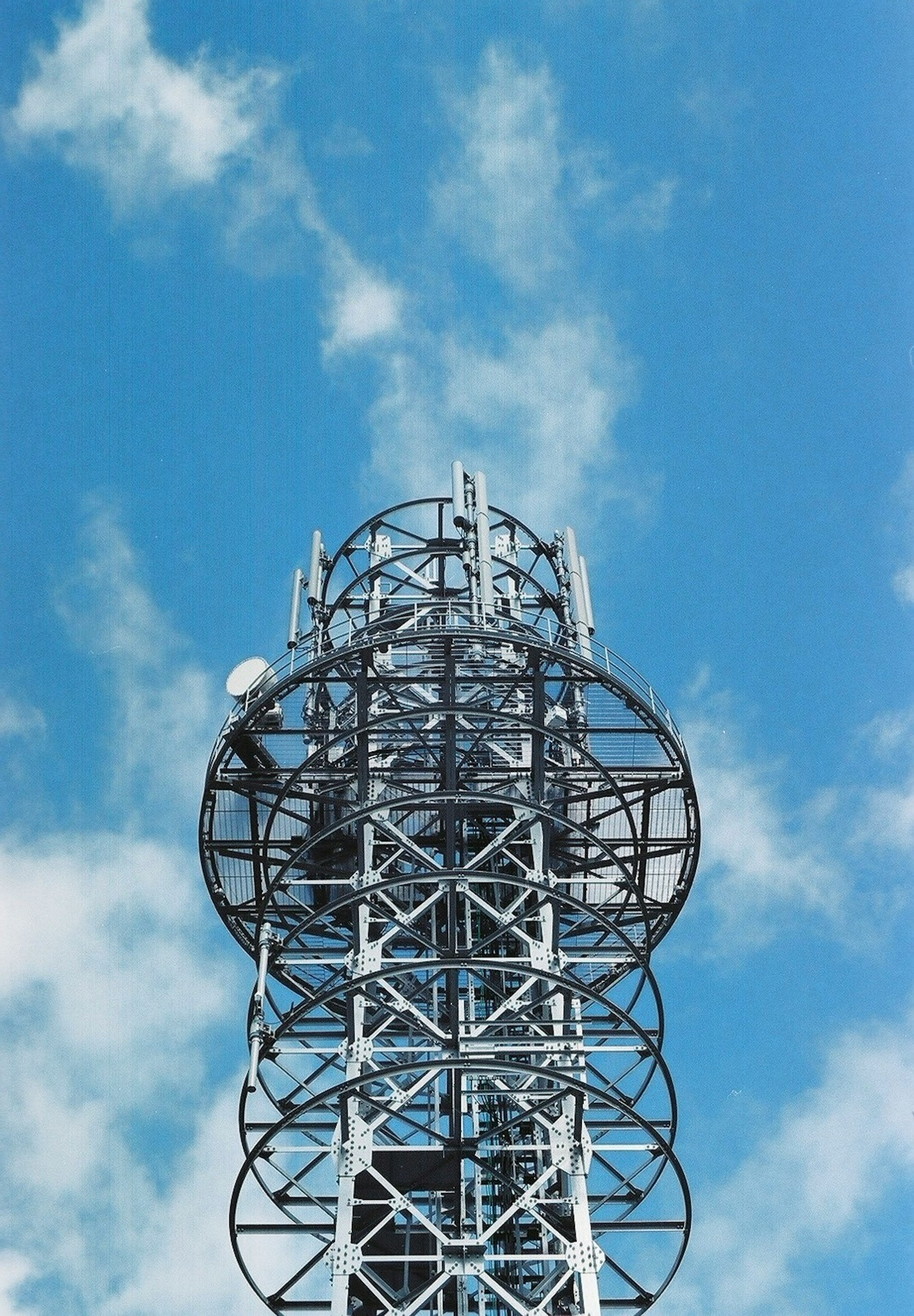 Worker on top of a communication tower against a blue sky